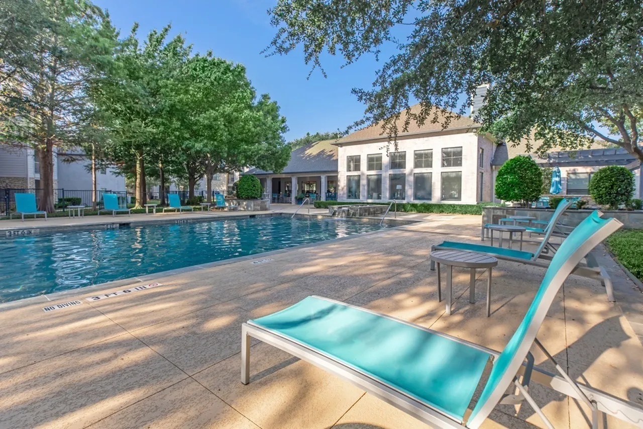 Resort-style swimming pool, turquoise lounge chairs, poolside deck, landscaping, clubhouse