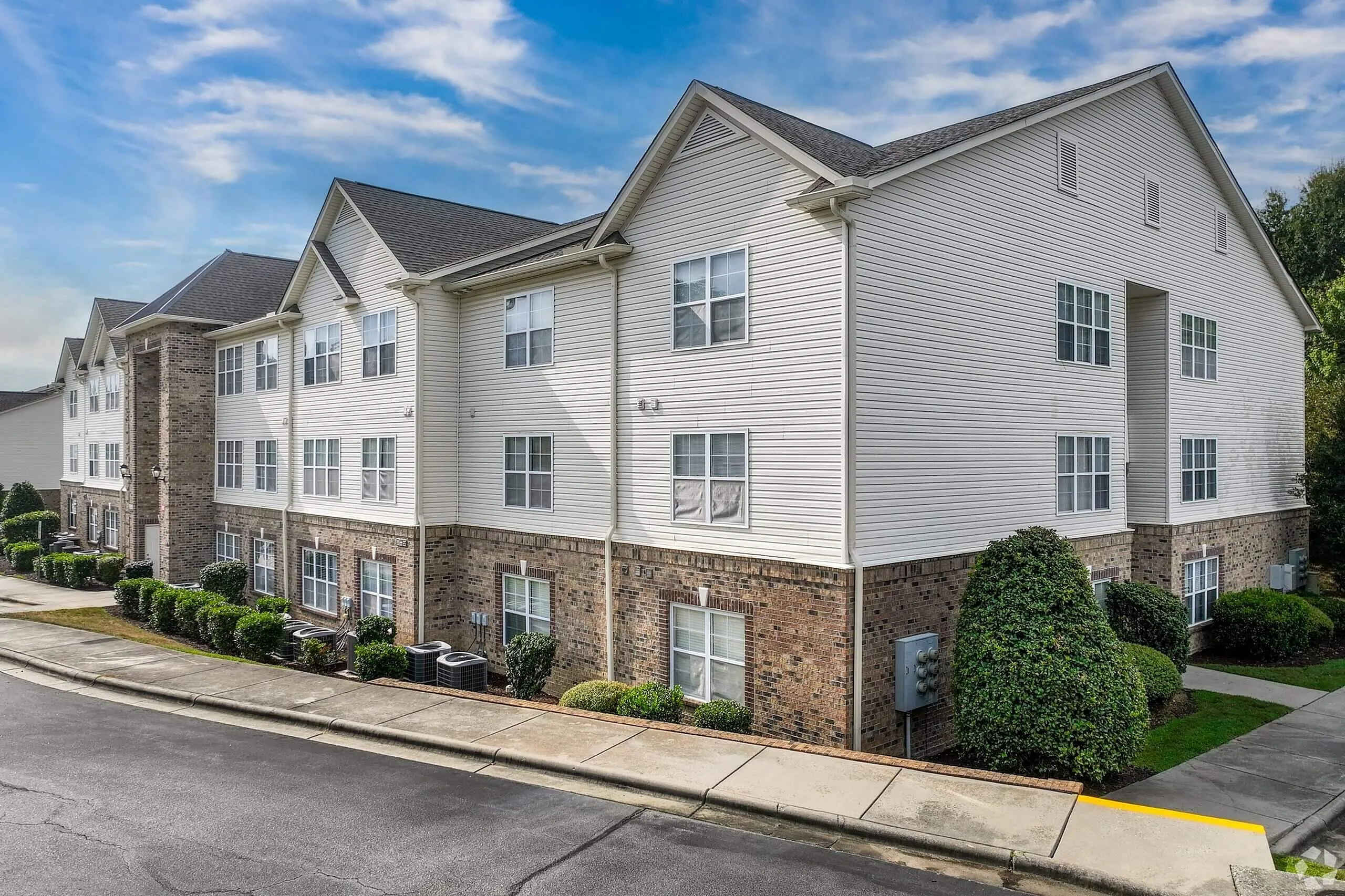 Residential building exterior, brick and siding, multiple windows, landscaping