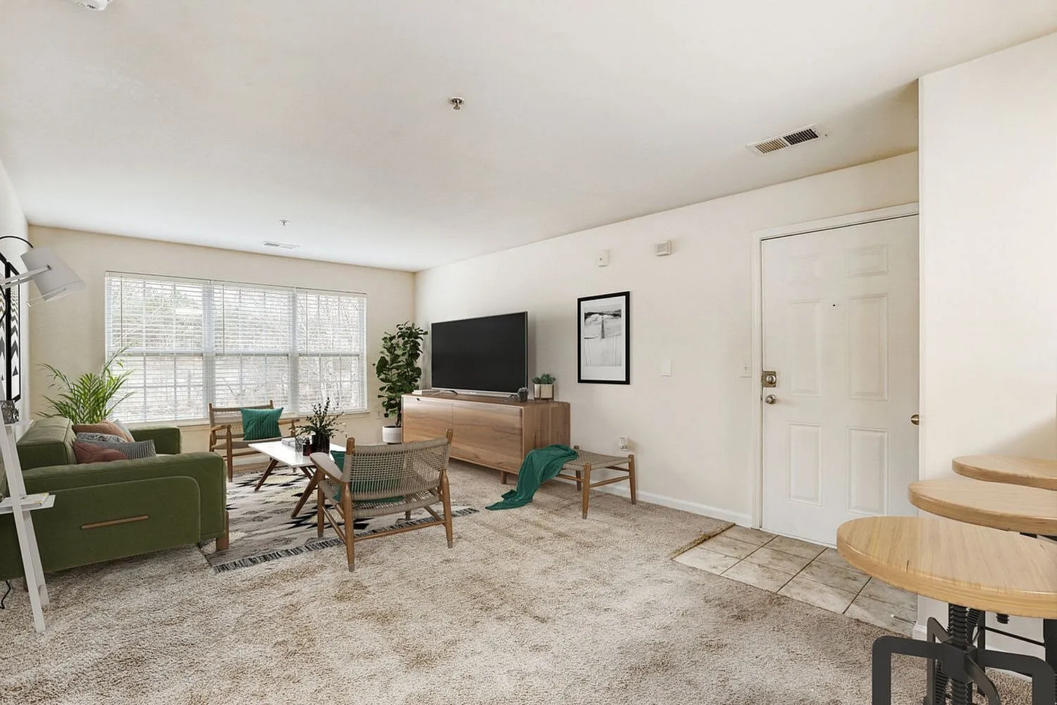 Living room, wood-style plank flooring, green upholstered sofa, media console with TV, natural light from windows