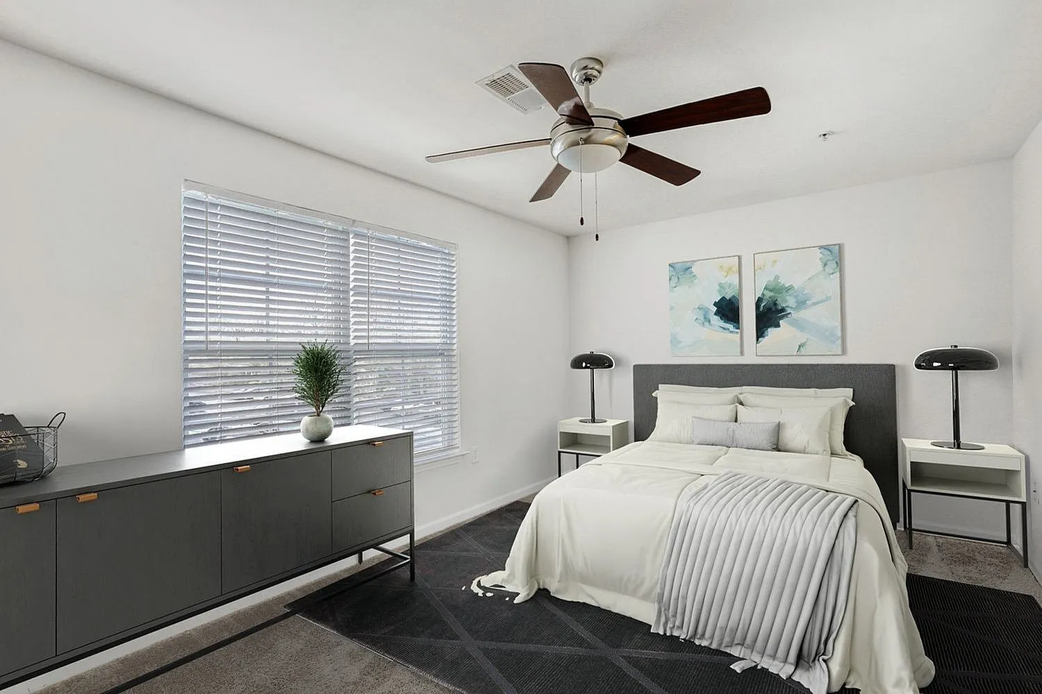 Primary bedroom, ceiling fan, gray upholstered headboard, wood-style plank flooring, ensuite bathroom