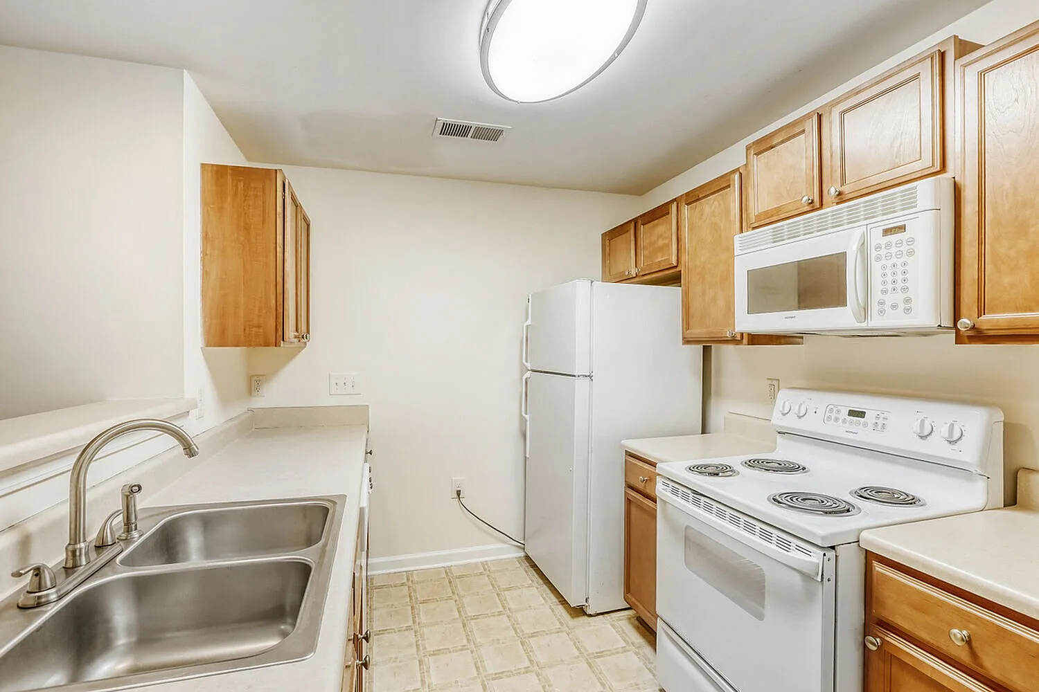 Kitchen, wood cabinetry, white appliances, stainless sink, tile flooring