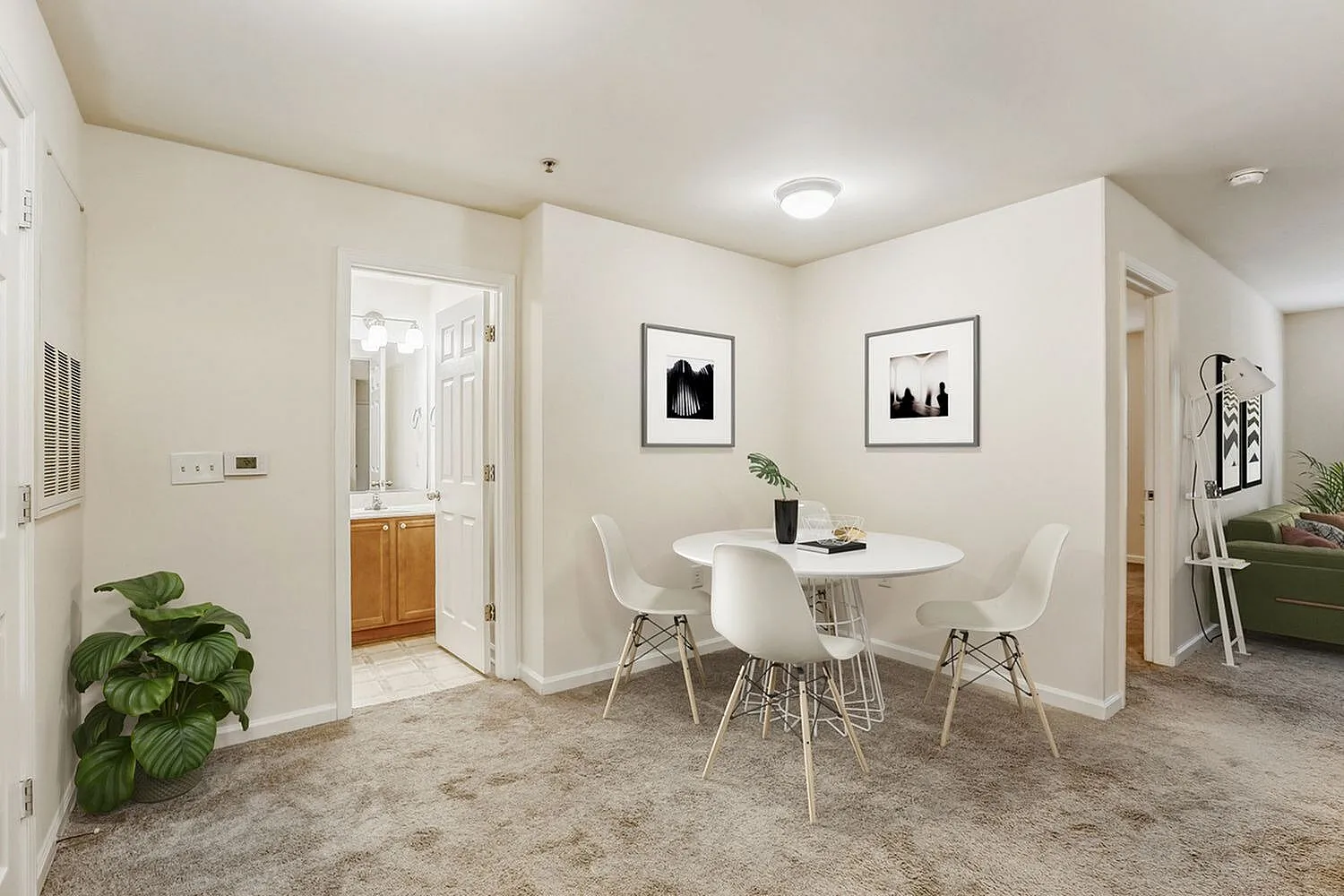 Dining area, white round table, eames-style chairs, gray carpet, framed wall art