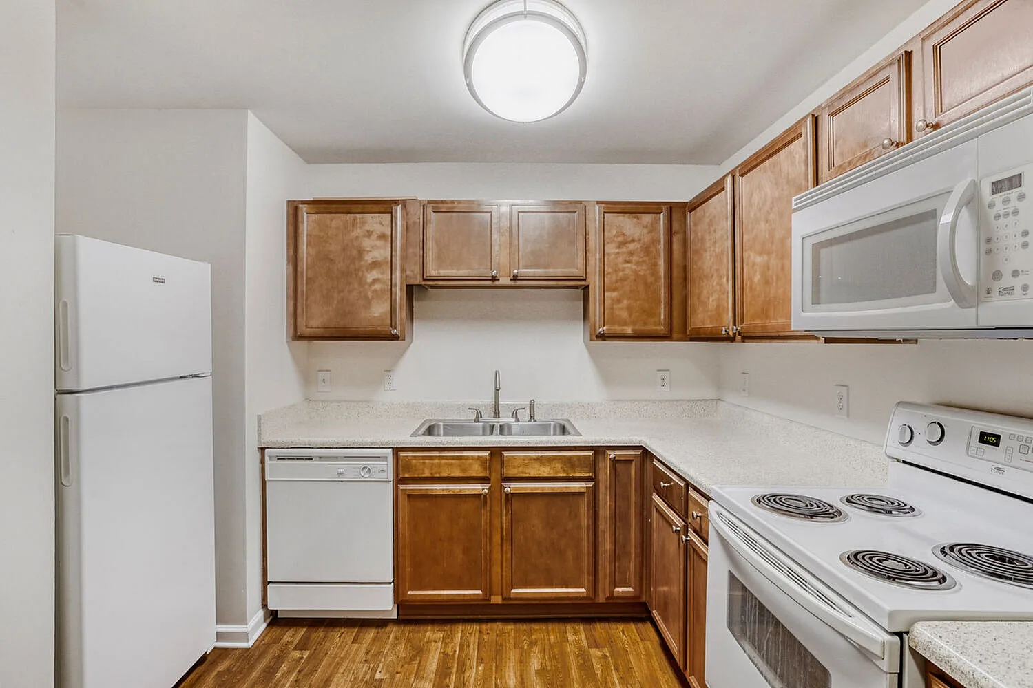 Kitchen, wood cabinetry, white appliances, wood-style plank flooring, stainless microwave