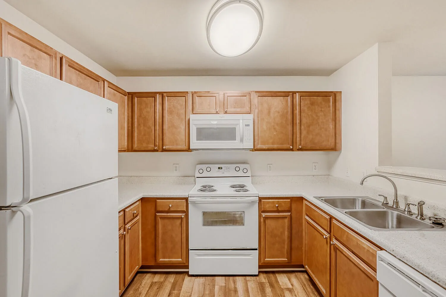 Kitchen, wood cabinetry, white appliances, laminate countertops, wood-style plank flooring