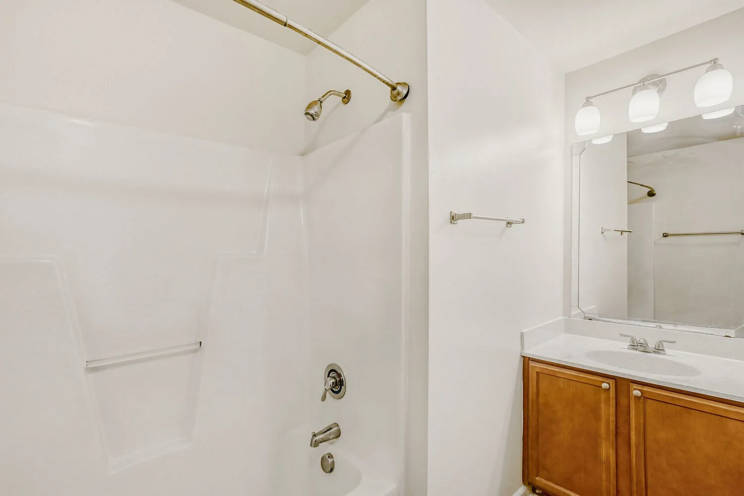 Bathroom, wood cabinetry vanity, marble countertop, framed mirror with lighting, glass shower enclosure