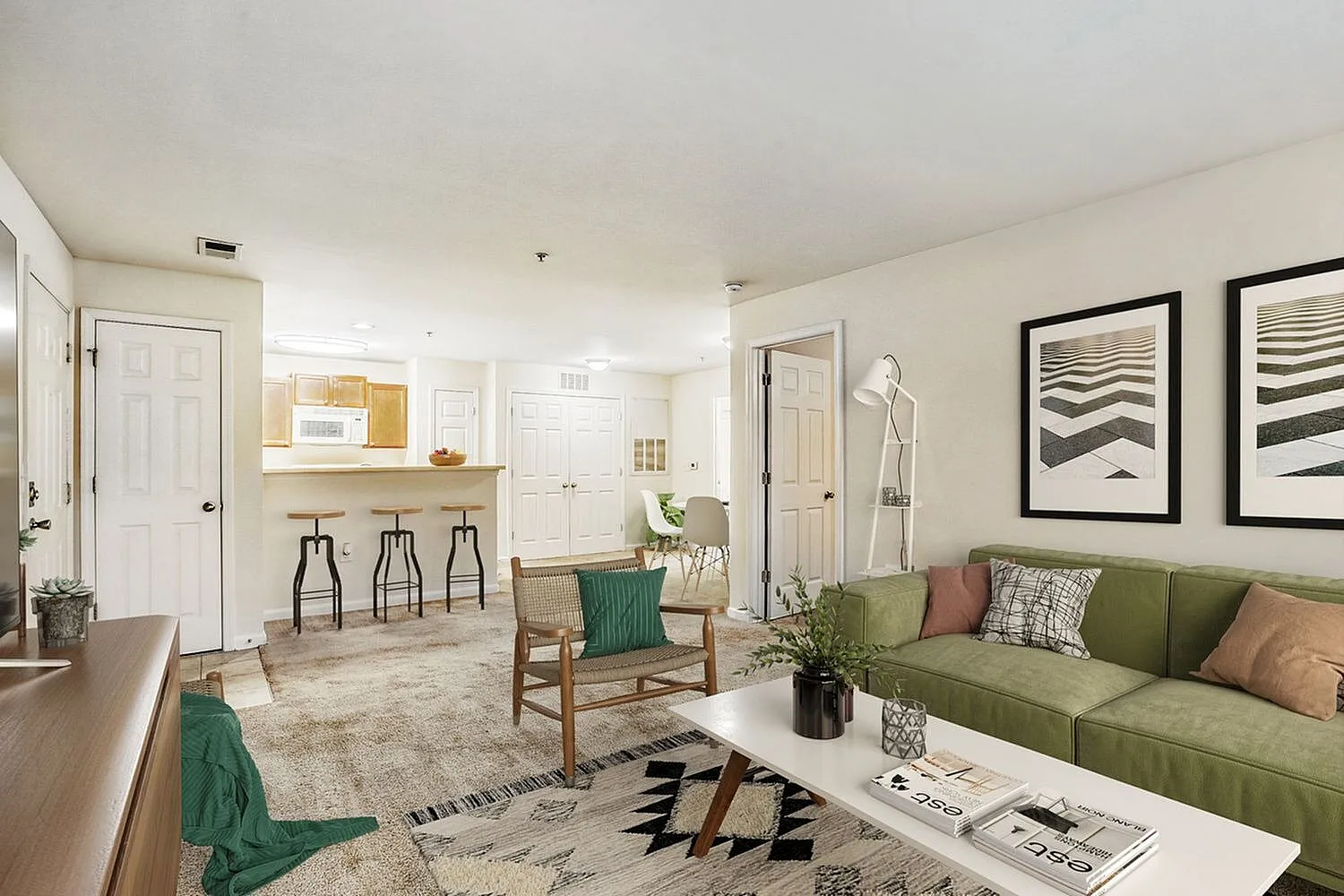 Living room and kitchen, green upholstered sofa, wood-style plank flooring, white cabinetry