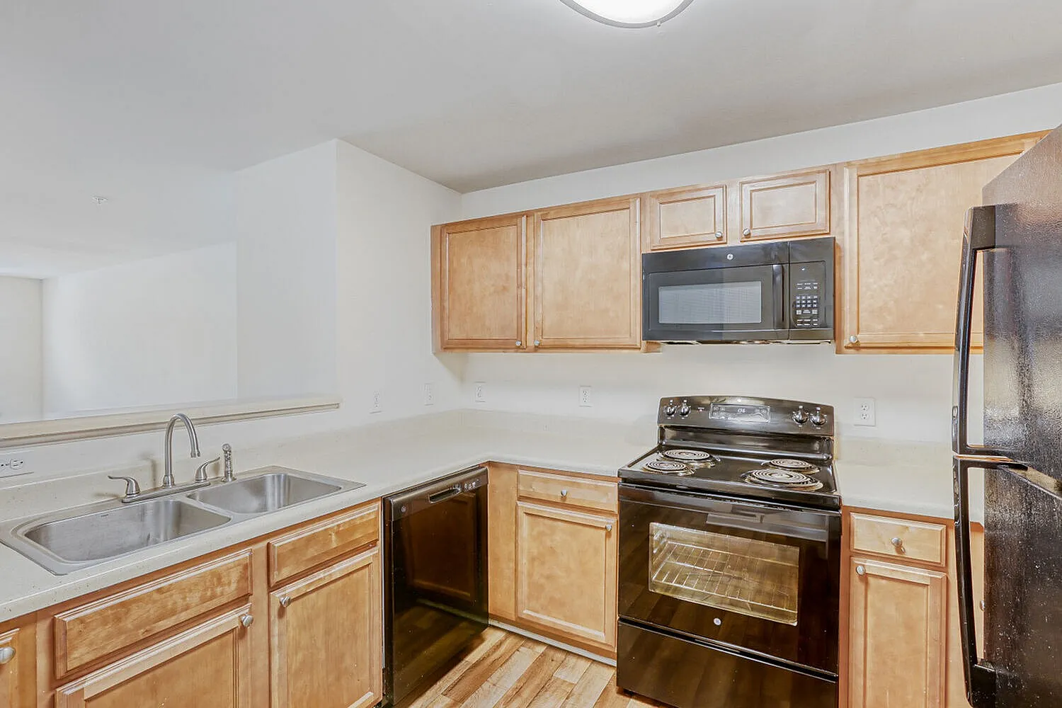 Kitchen, natural wood cabinetry, stainless steel appliances, white countertops, wood-style plank flooring