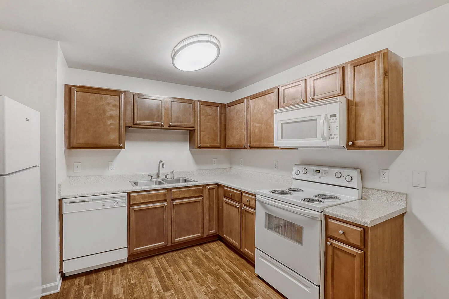 Kitchen, wood cabinetry, white appliances, laminate countertops, wood-style plank flooring