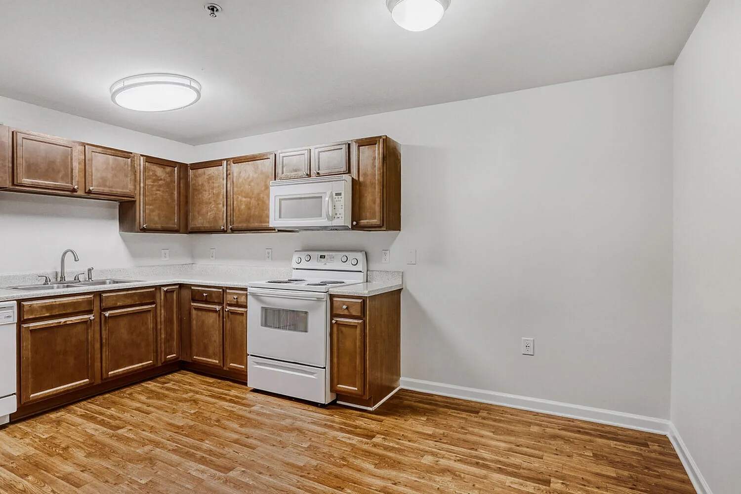 Kitchen, wood cabinetry, white appliances, wood-style plank flooring, recessed lighting