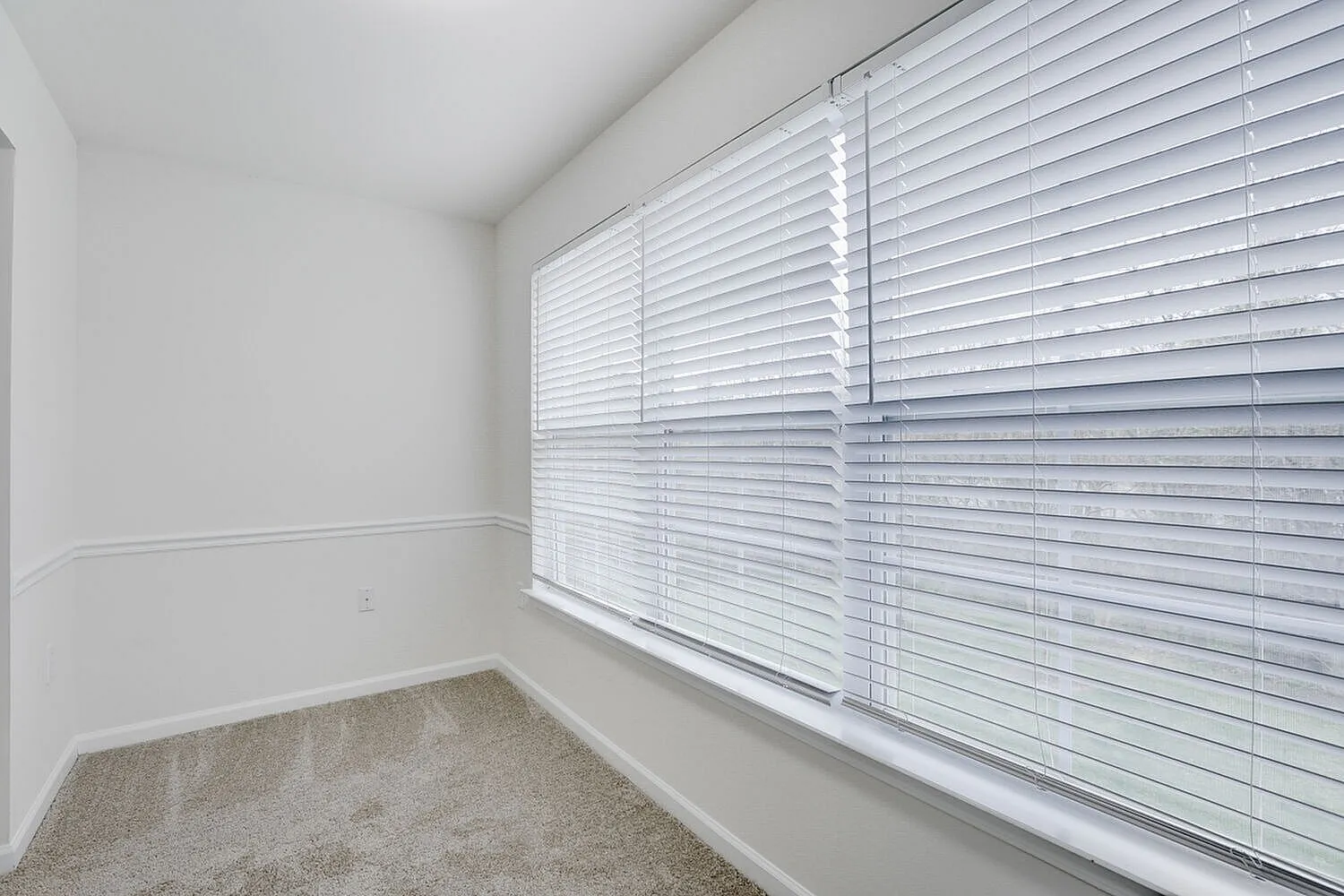 Bedroom, large window with white horizontal blinds, beige carpet, white walls