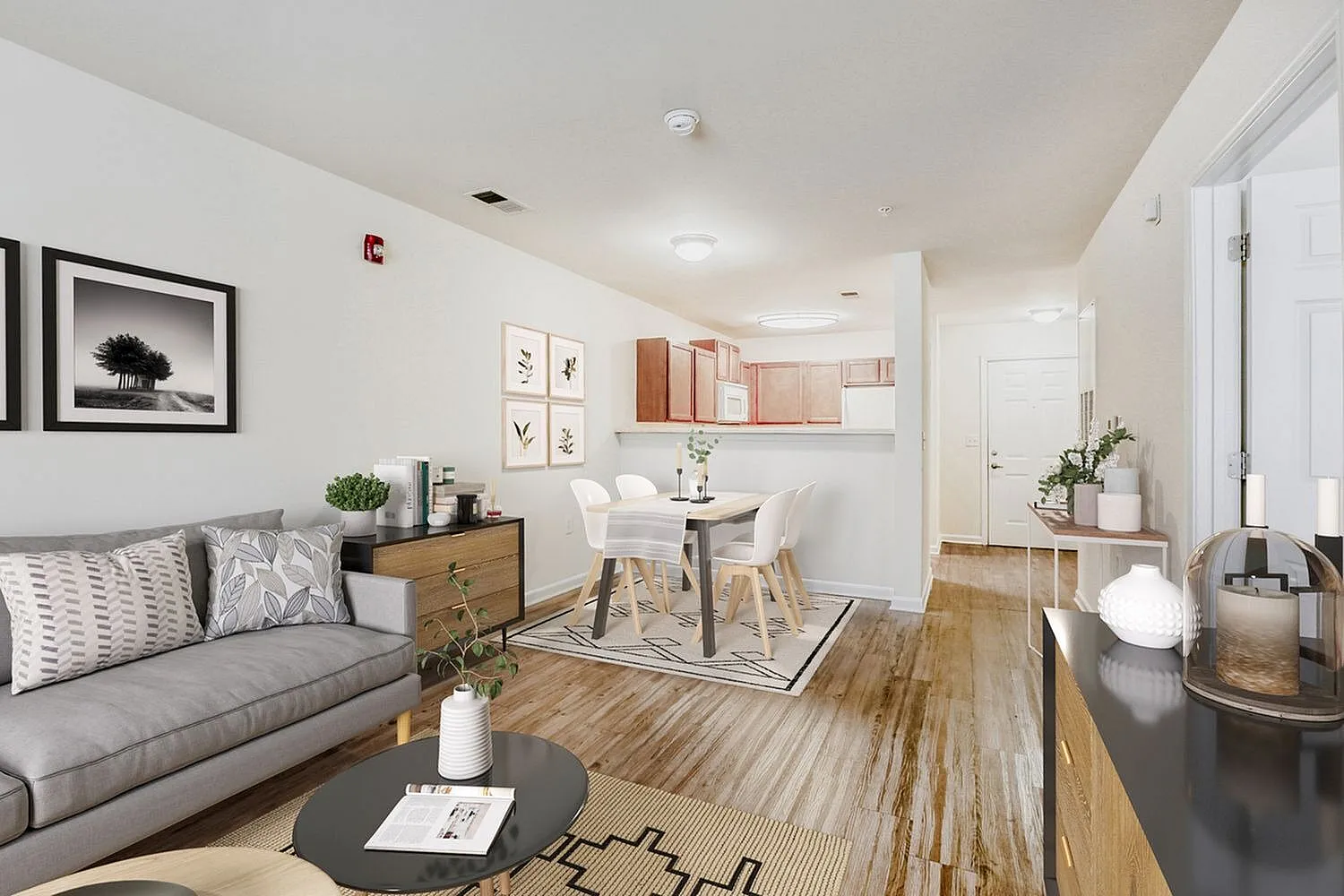 Open-concept living and dining area, wood-style plank flooring, gray sofa, wood dining table with white chairs, kitchen with light cabinetry