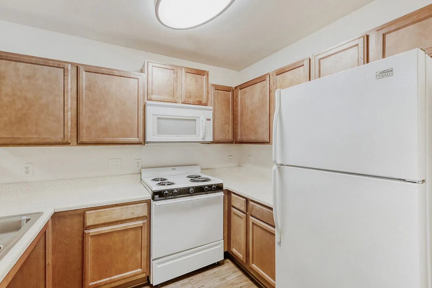 Kitchen, wood cabinetry, white appliances, laminate countertops, wood-style plank flooring