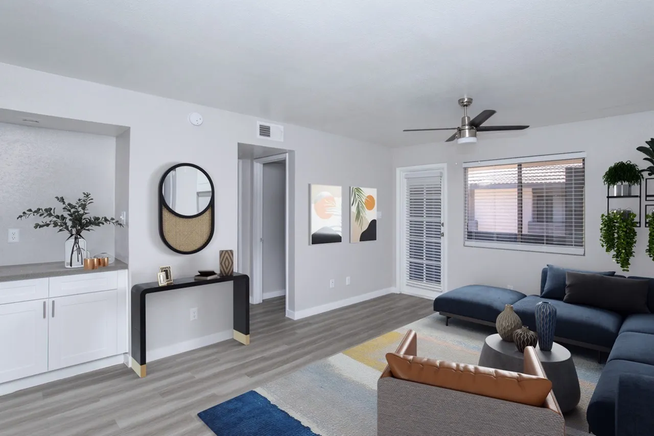 Living room and kitchen, wood-style plank flooring, dark blue sofa, ceiling fan, white cabinetry