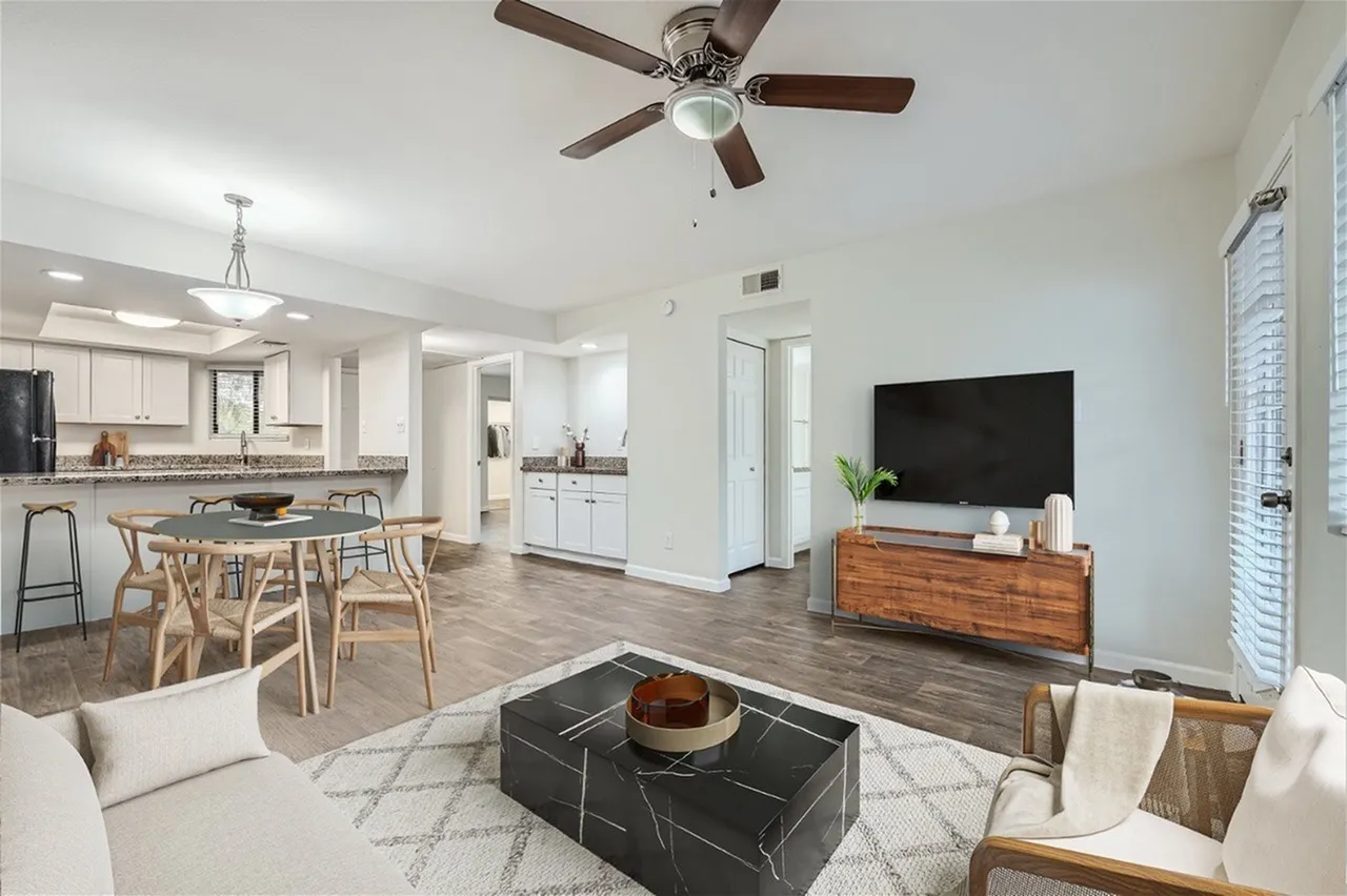 Open concept living and dining area, wood-style plank flooring, ceiling fan, television, dining table