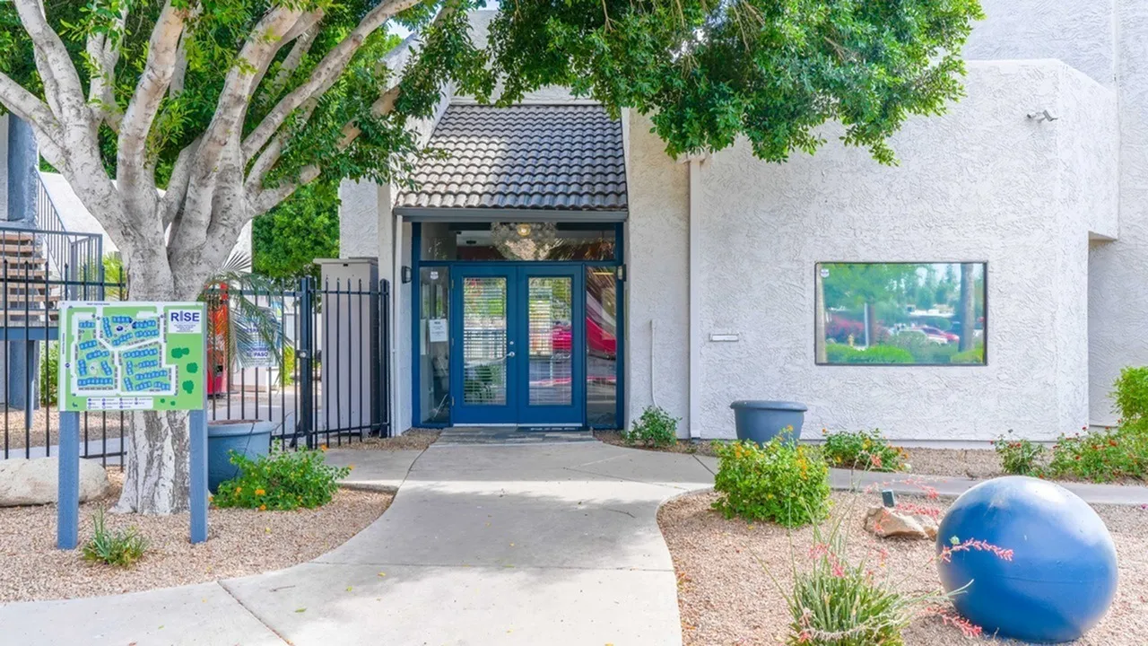 Building exterior, blue entry doors, white stucco walls, dark tile roof, mature tree, decorative landscaping, blue exercise ball