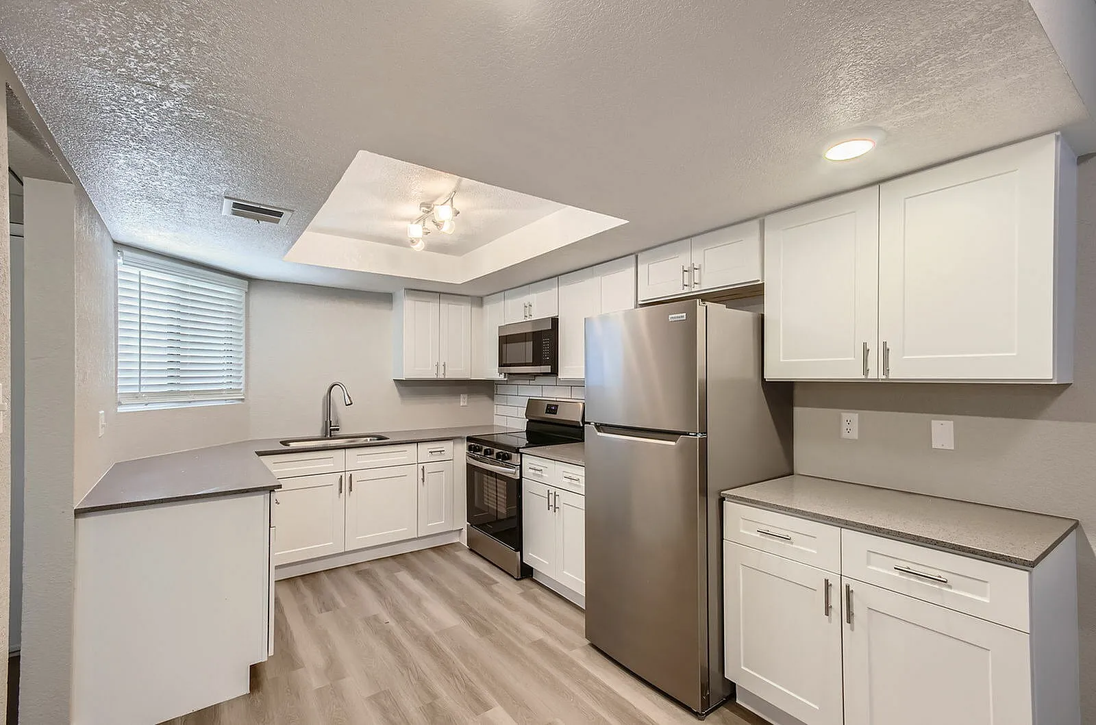 Kitchen, white shaker cabinetry, stainless steel appliances, wood-style plank flooring, recessed lighting