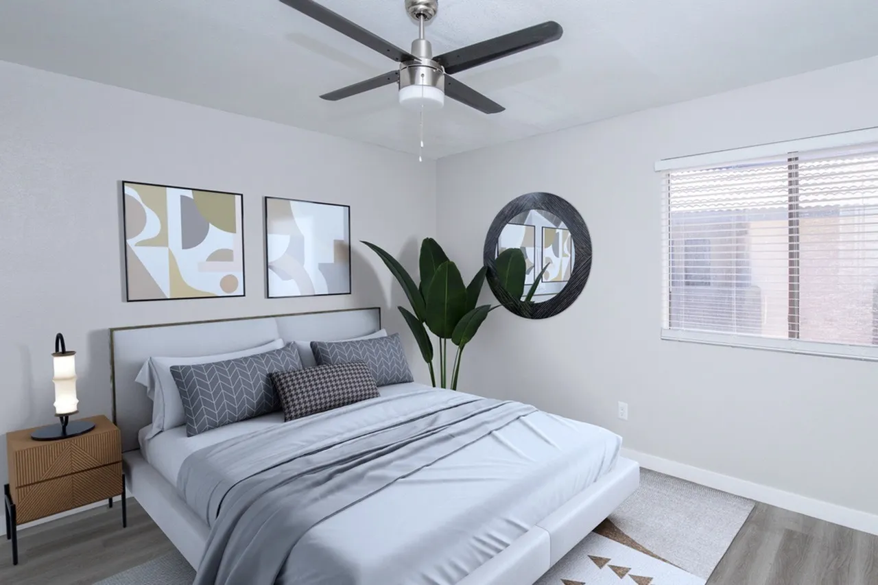 Primary bedroom, gray upholstered bed, ceiling fan, wood nightstand, round mirror, plant