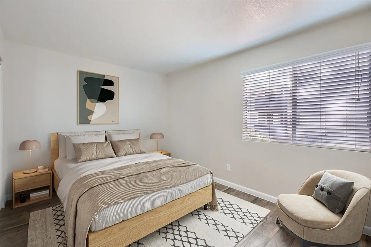Primary bedroom, wood-style plank flooring, wood bed frame, neutral bedding, modern abstract wall art