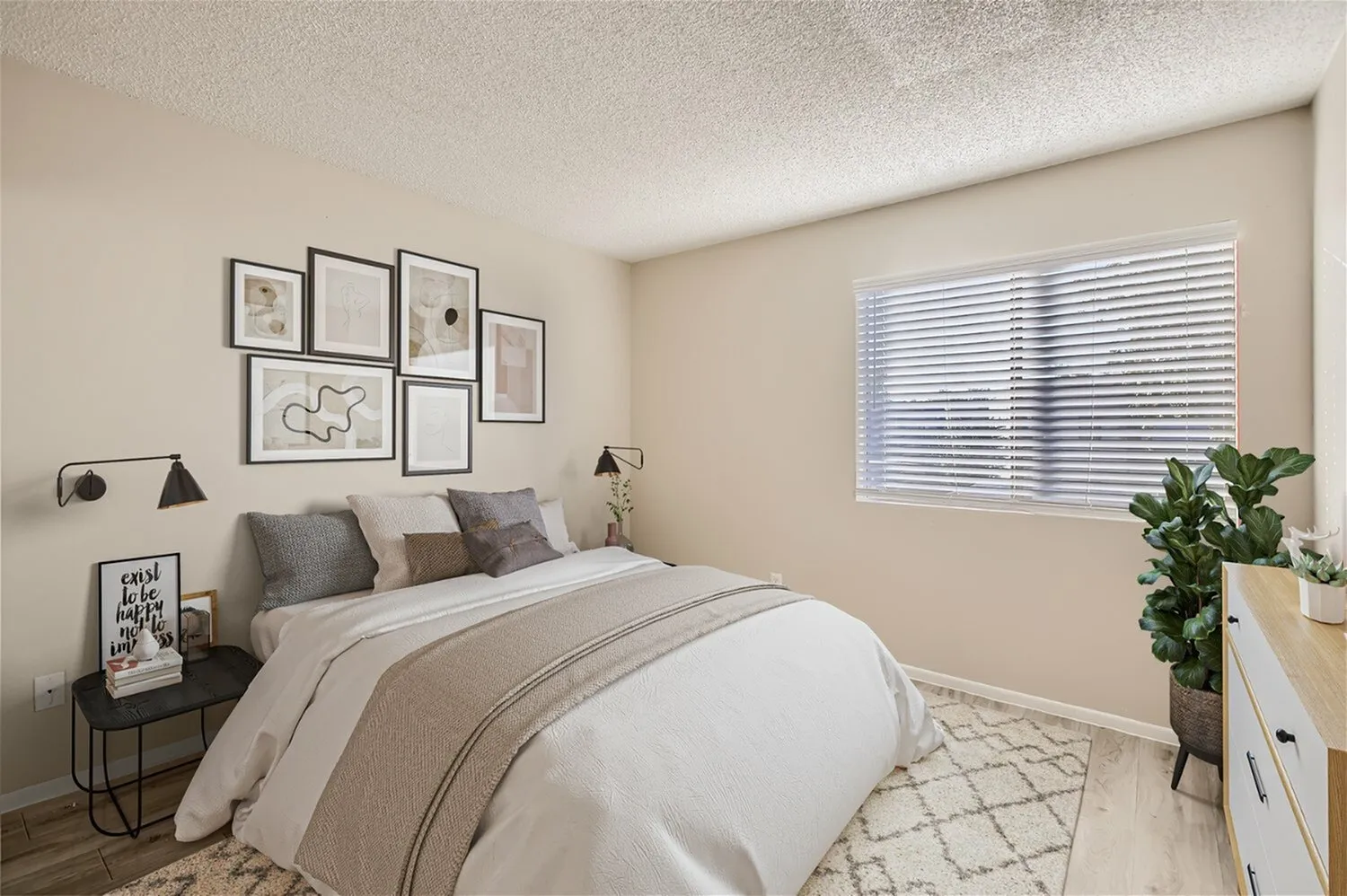 Primary bedroom, wood-style plank flooring, neutral bedding, framed wall art, blinds