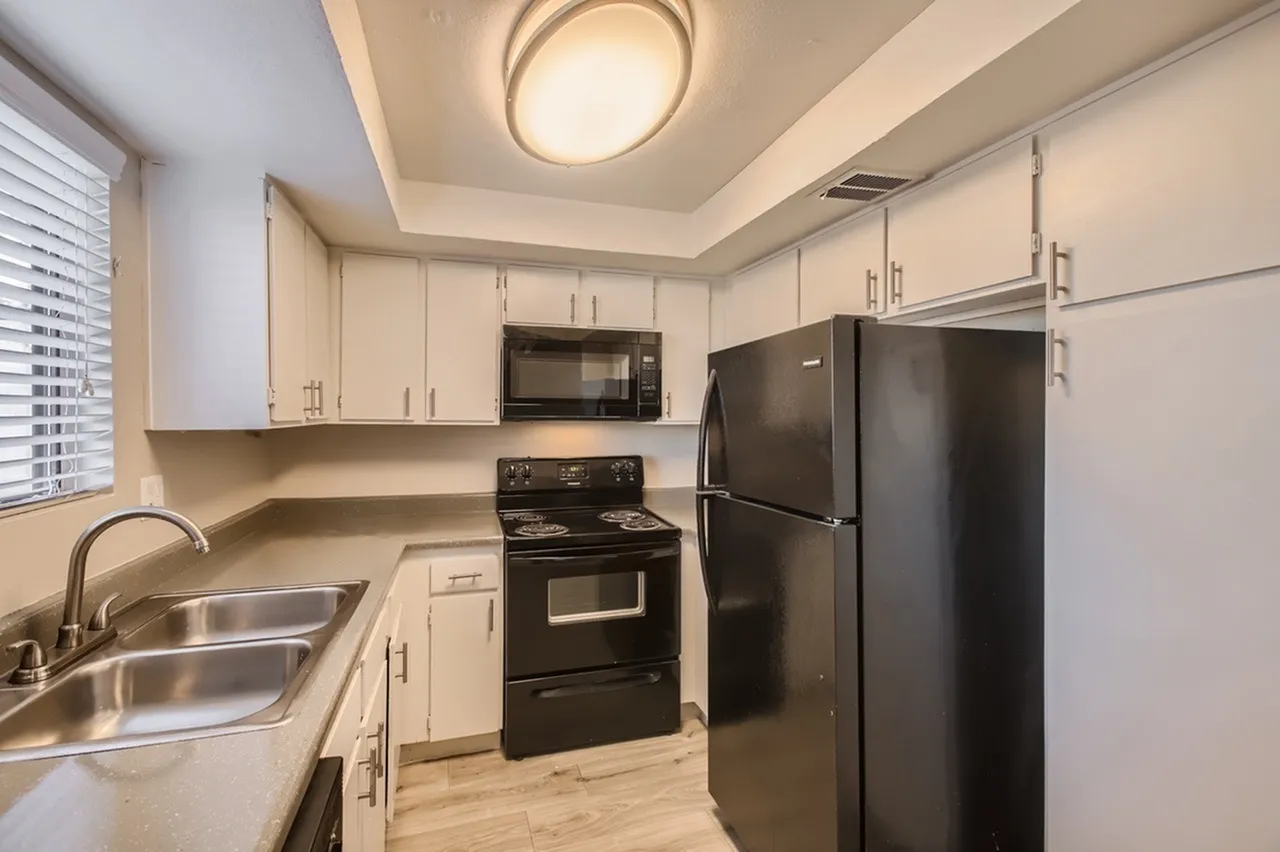 Kitchen, white shaker cabinetry, granite countertops, black appliances, wood-style plank flooring
