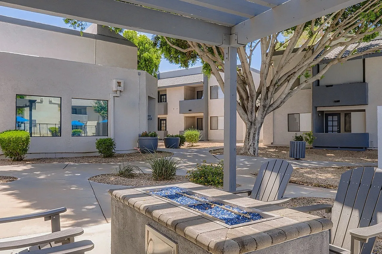 Courtyard with fire pit, Adirondack chairs, mature tree, concrete paving, residential buildings