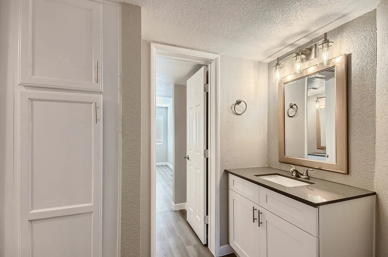 Bathroom, white cabinetry, black countertop, framed mirror, chrome hardware