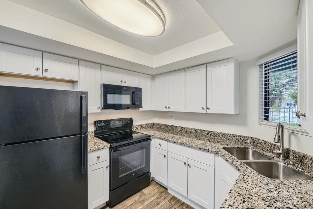 Kitchen, white shaker cabinetry, speckled granite countertops, stainless steel sink, black appliances
