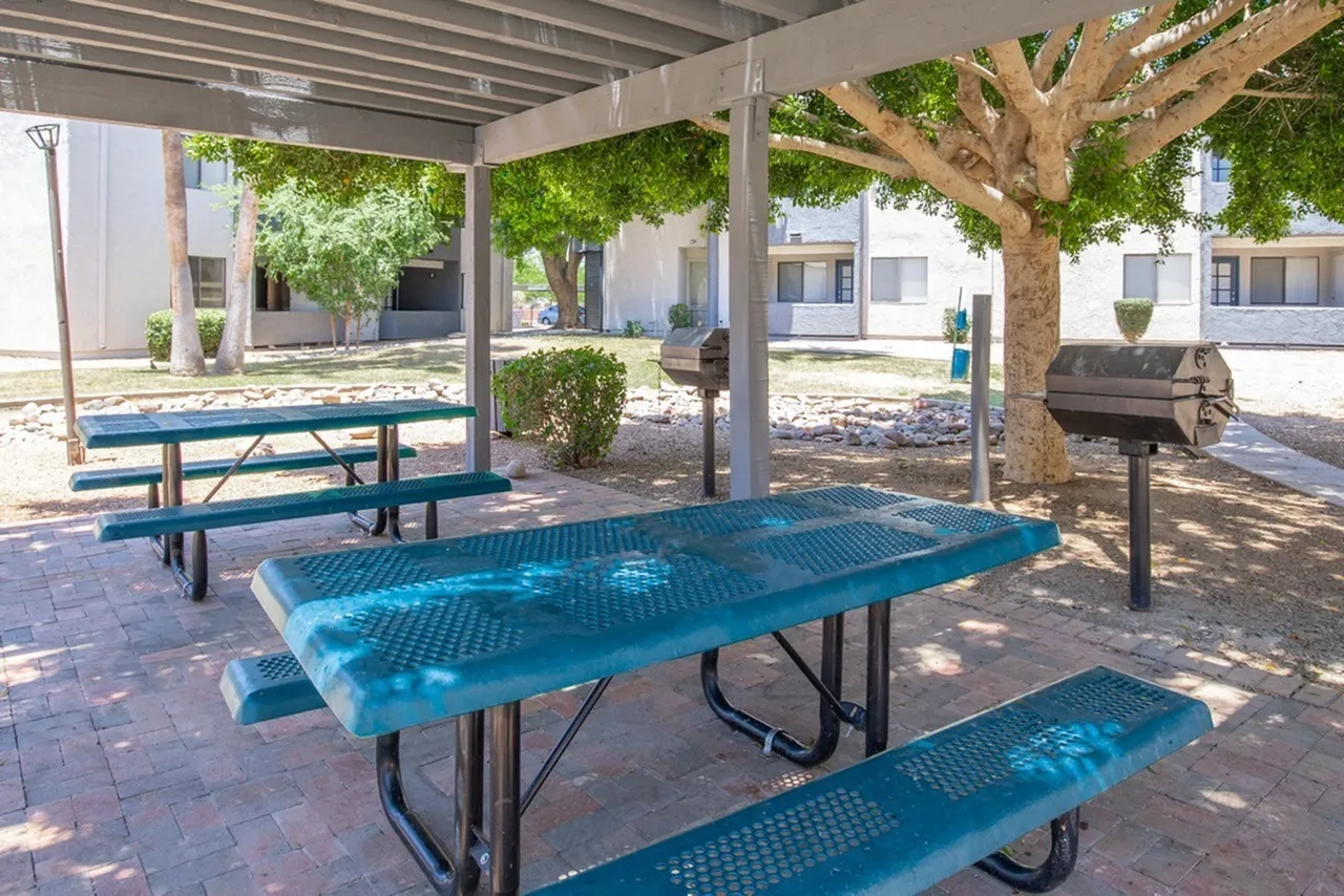 Covered picnic area, blue metal picnic tables, brick paving, shade trees, grills