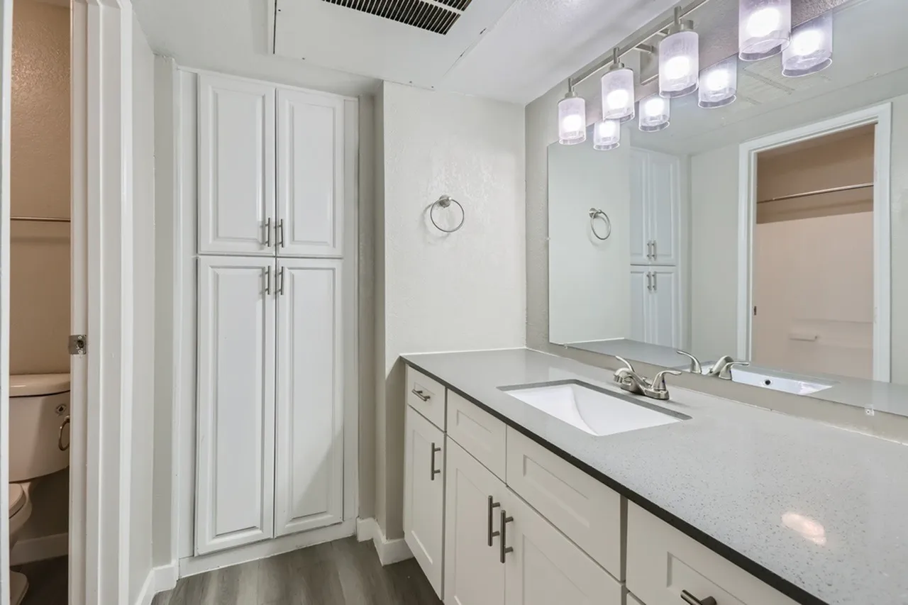 Primary bathroom, white shaker cabinetry, quartz countertop, vessel sink, framed mirror, pendant lighting