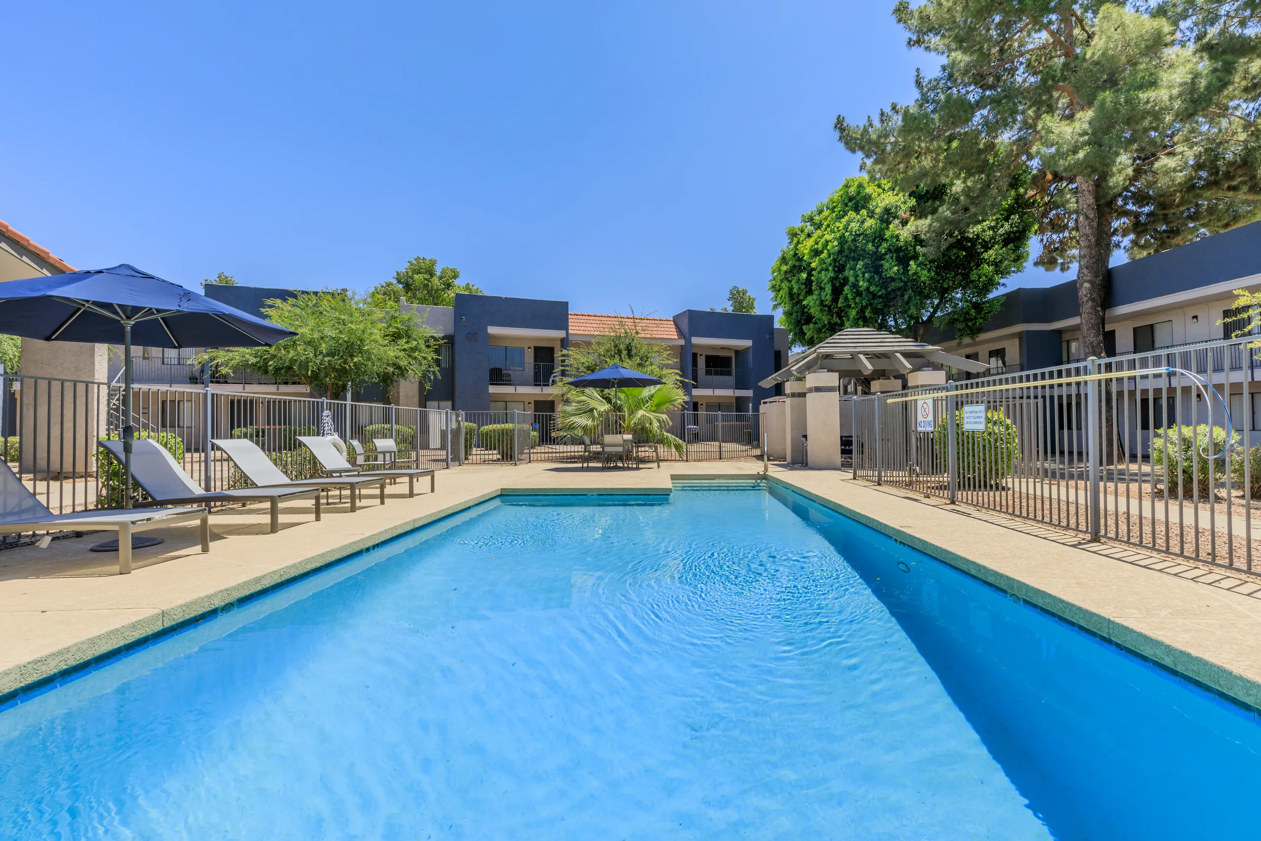 Community swimming pool with lounge chairs and umbrella