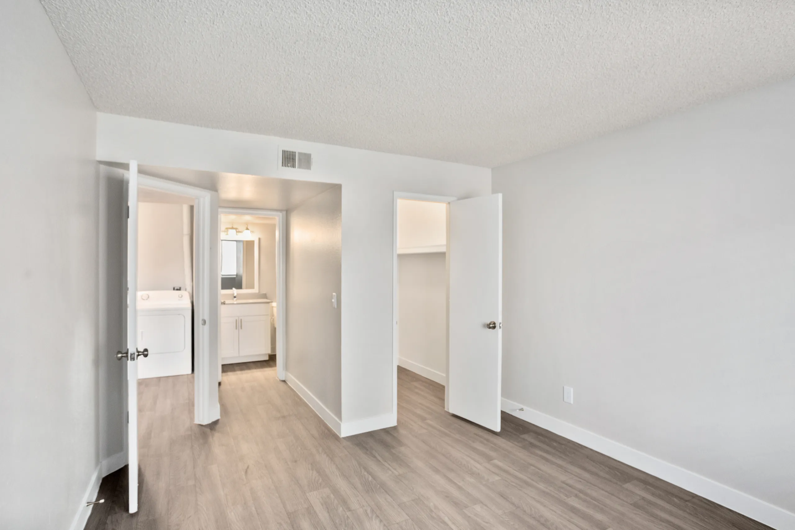 Bedroom with doors leading to laundry area, ensuite bathroom, and closet