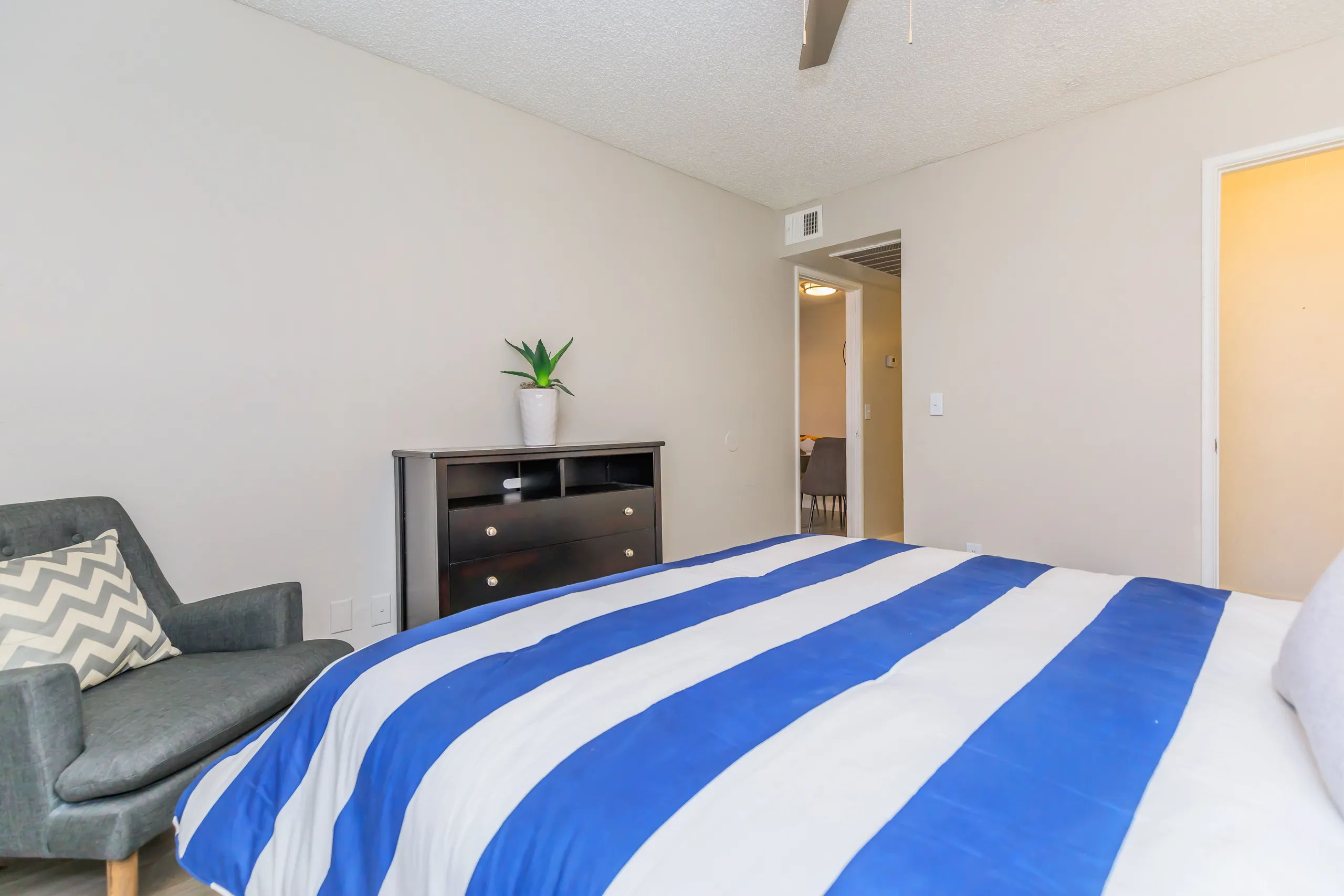 Bedroom with accent chair, dresser, and doorway view into living area
