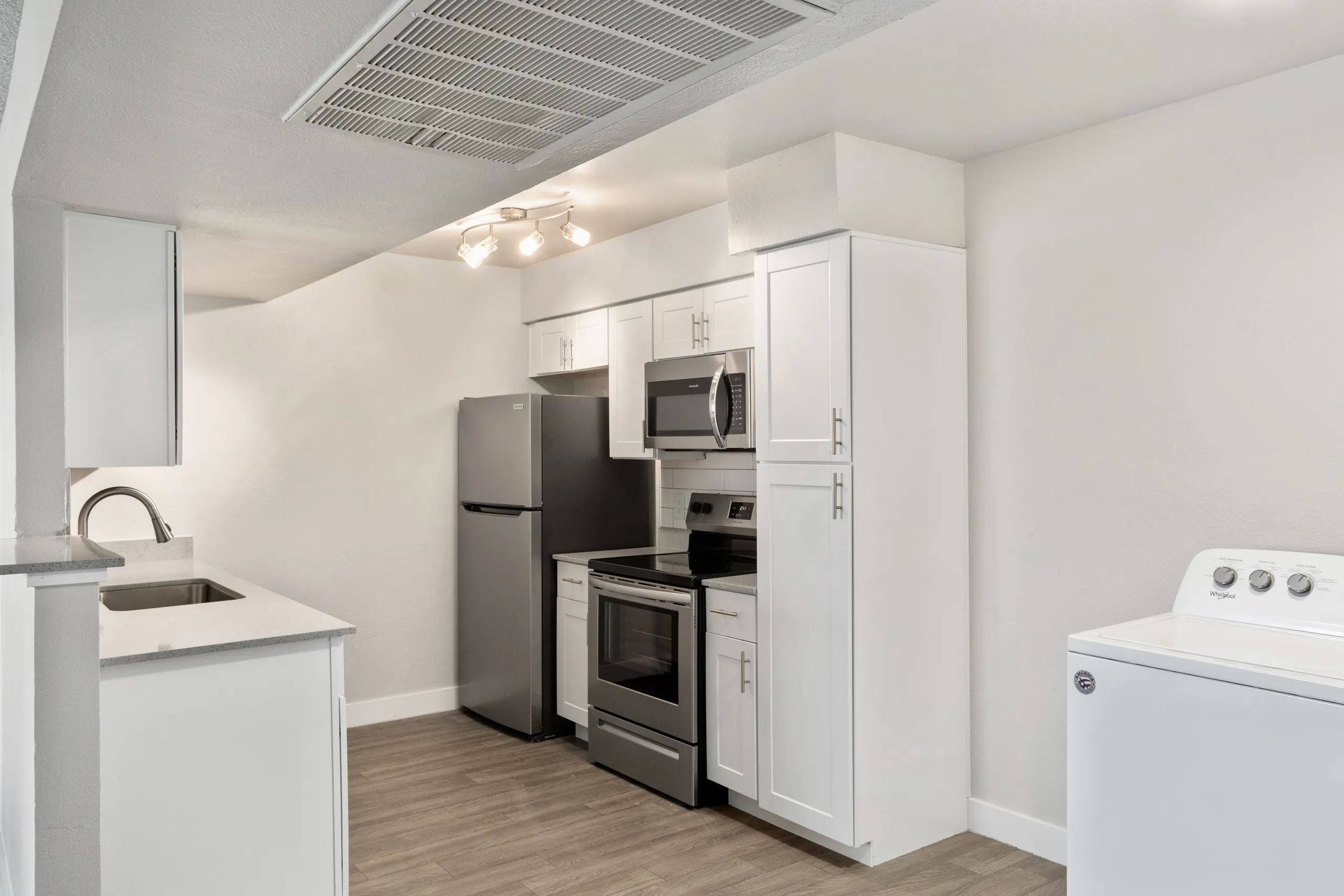 Kitchen with white cabinetry, stainless appliances, and adjacent laundry