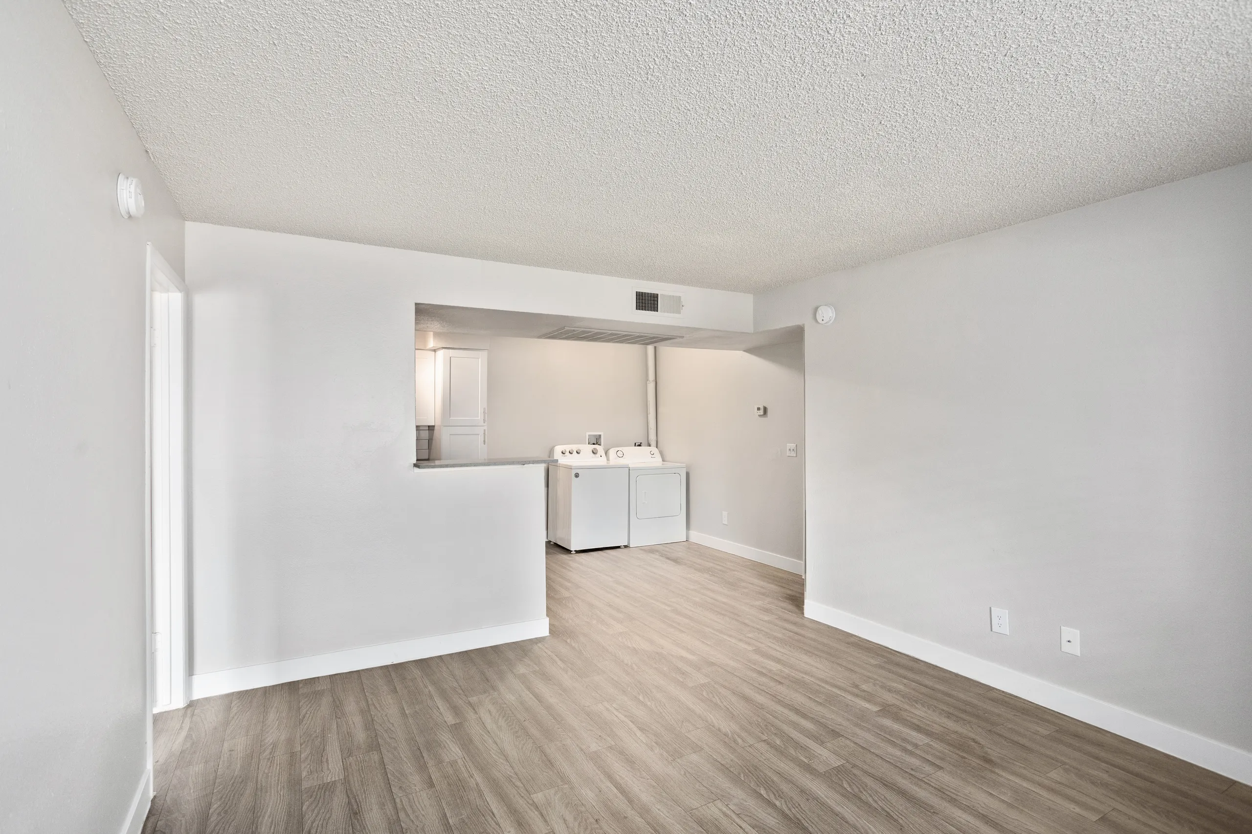 Living room opening into kitchen with in-unit washer and dryer