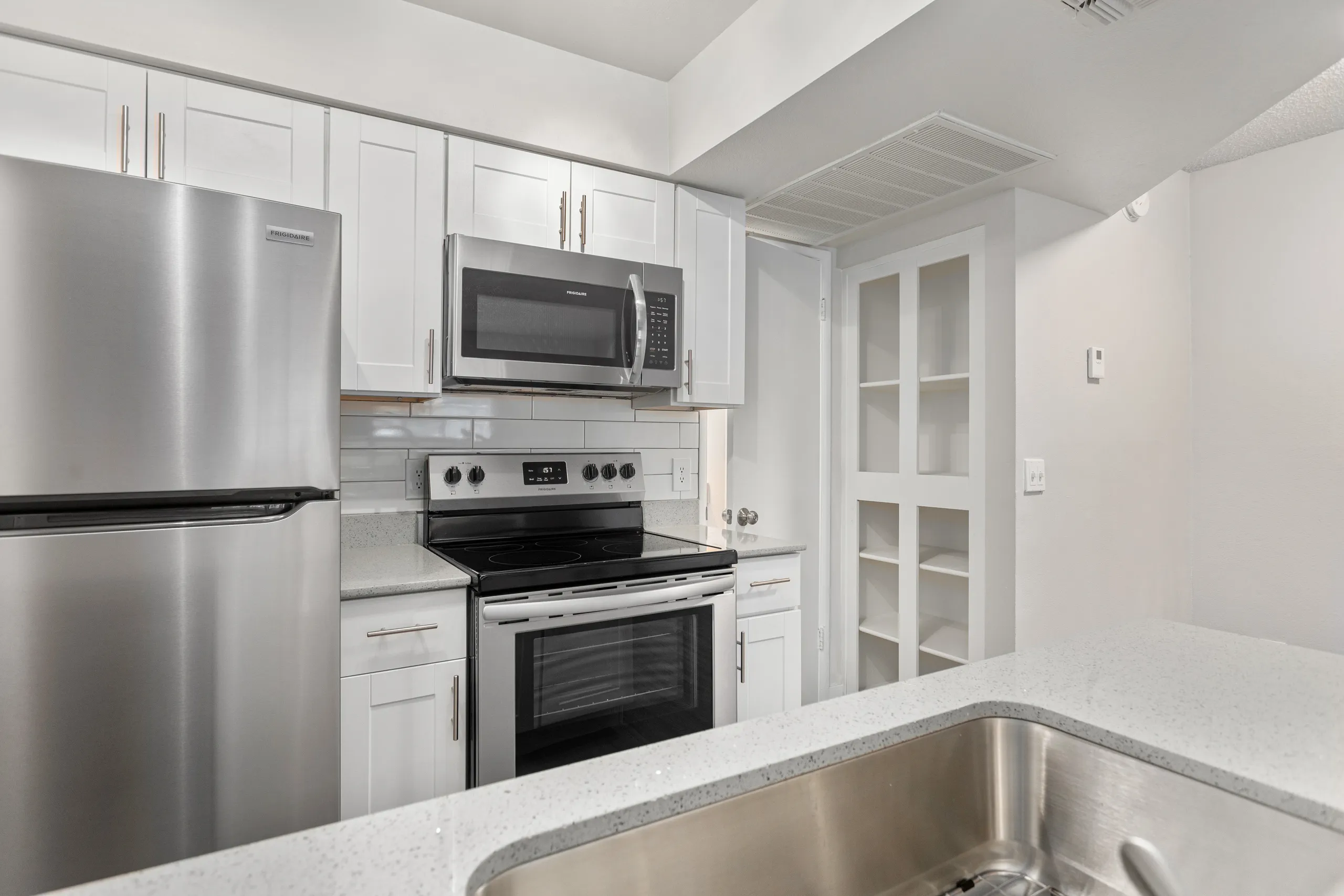 Kitchen with stainless appliances and adjacent open pantry shelving