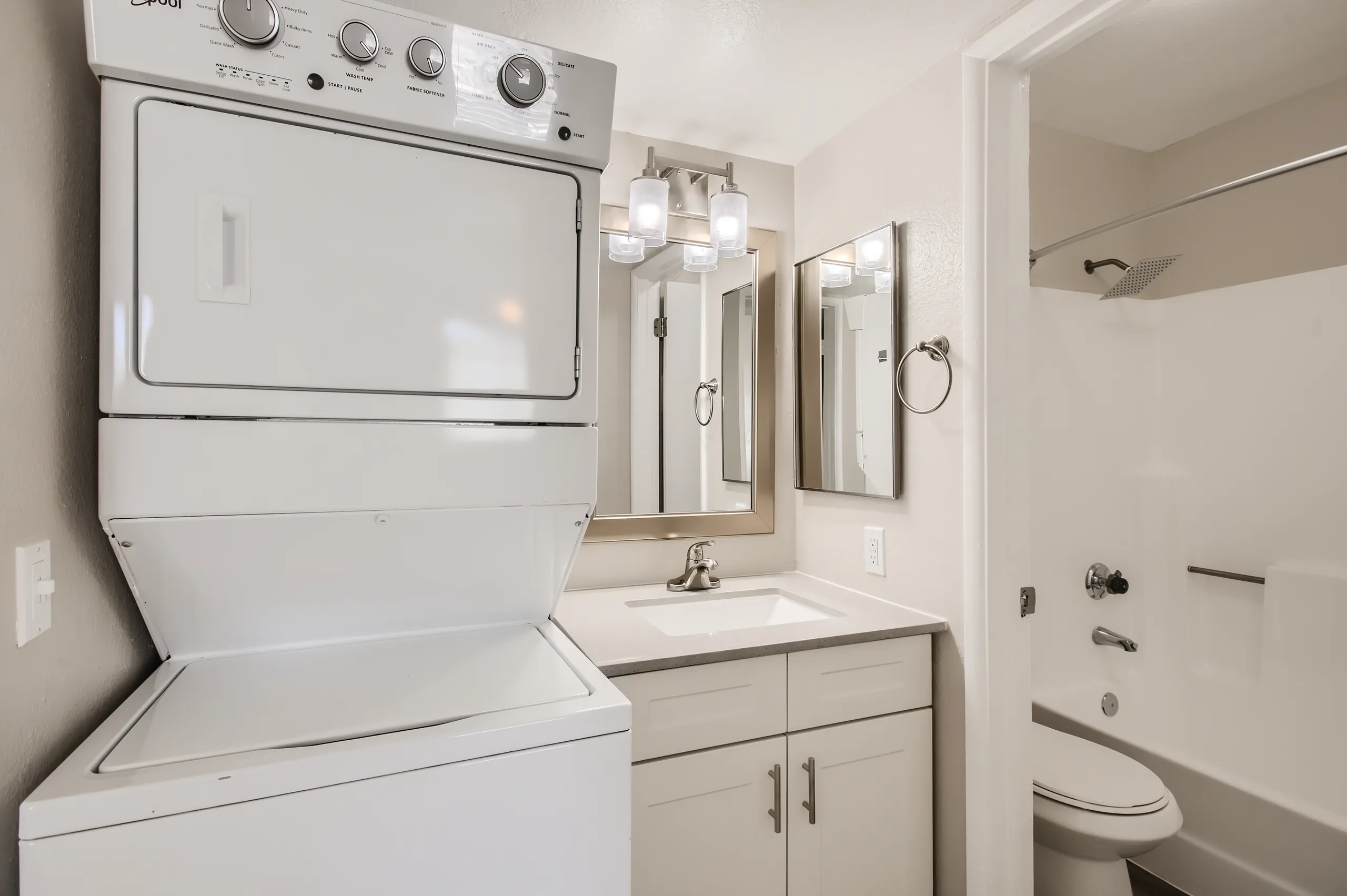 Primary bathroom with in-unit stacked washer and dryer, vanity, and walk-in shower