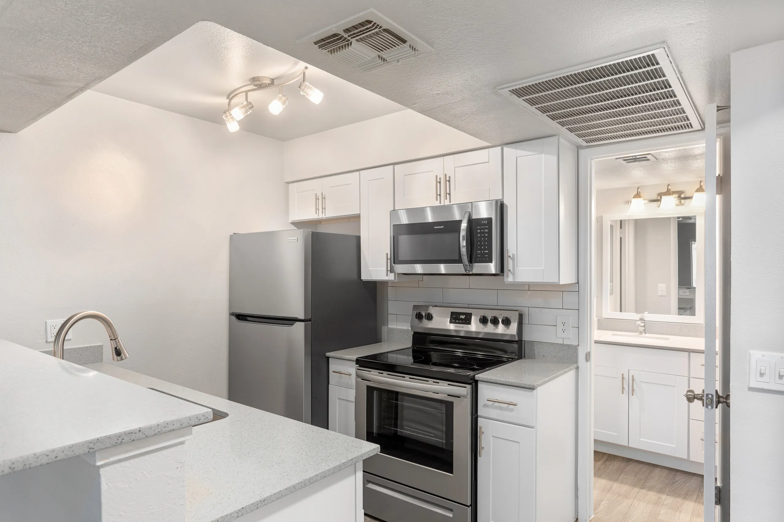 Kitchen with white shaker cabinets, quartz counters, and stainless appliances