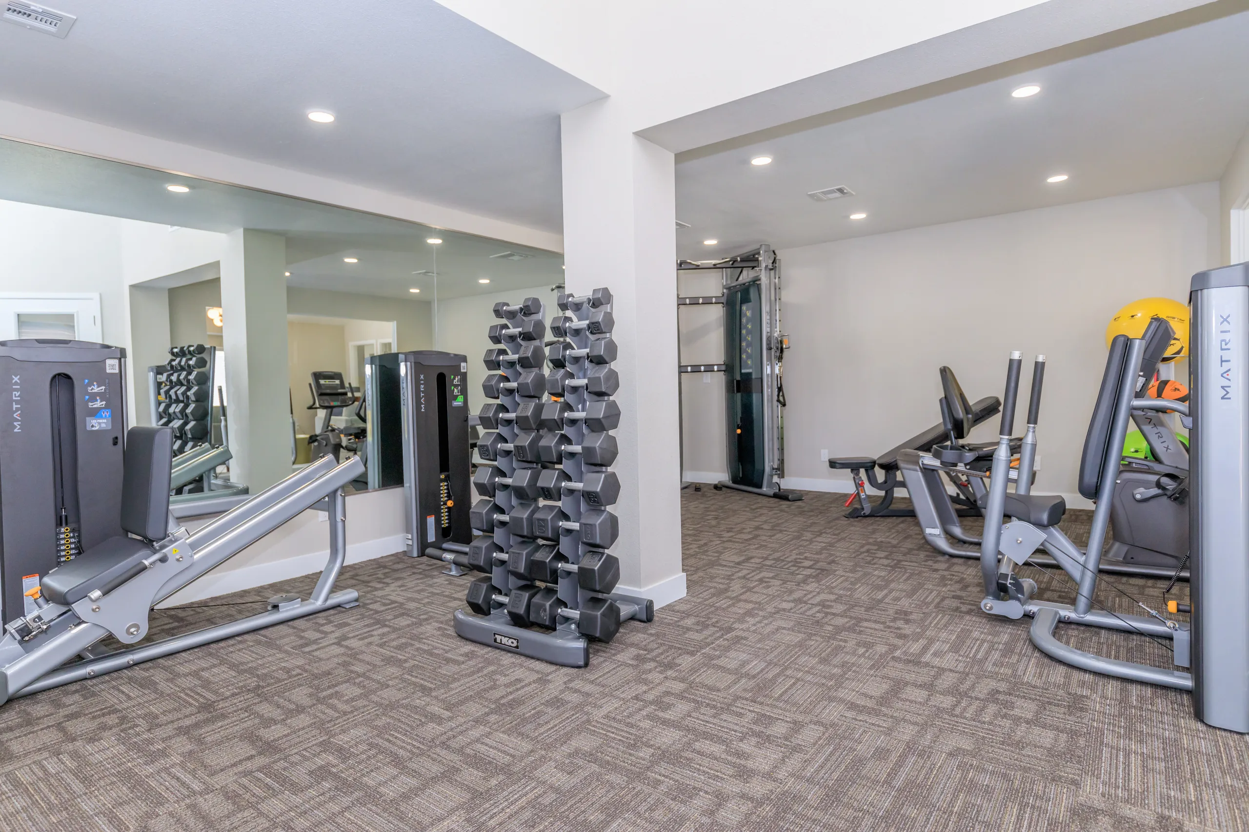 Fitness center with cardio equipment, weight machines, and dumbbell rack