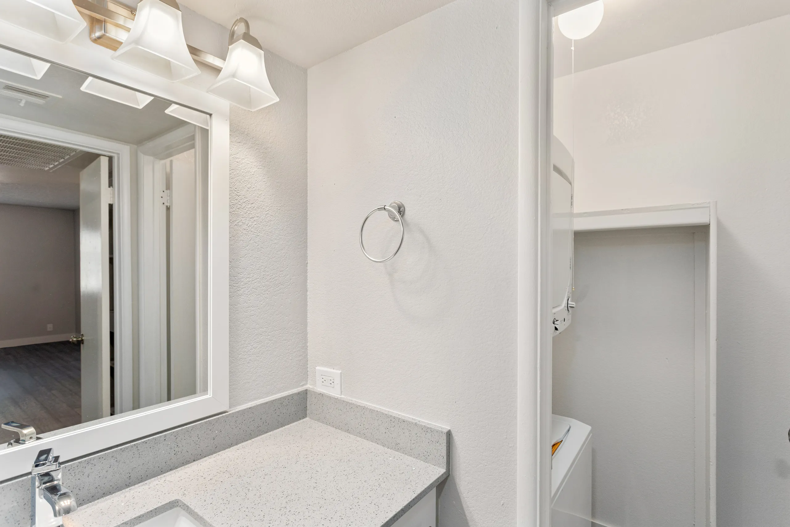Bathroom vanity with quartz counter, mirror, and towel ring, with in-unit stacked washer and dryer