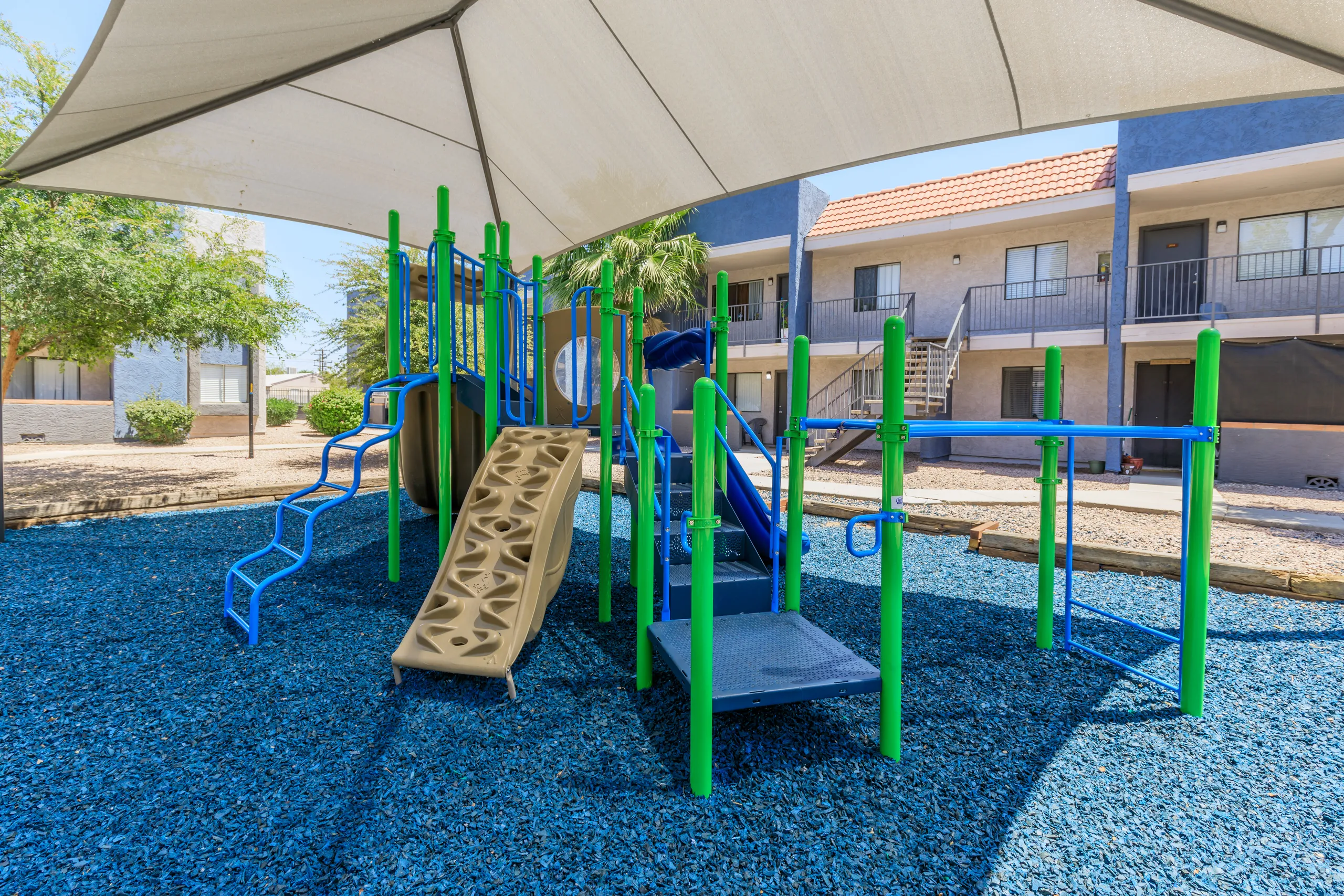 Shaded playground with slide and climbing structure