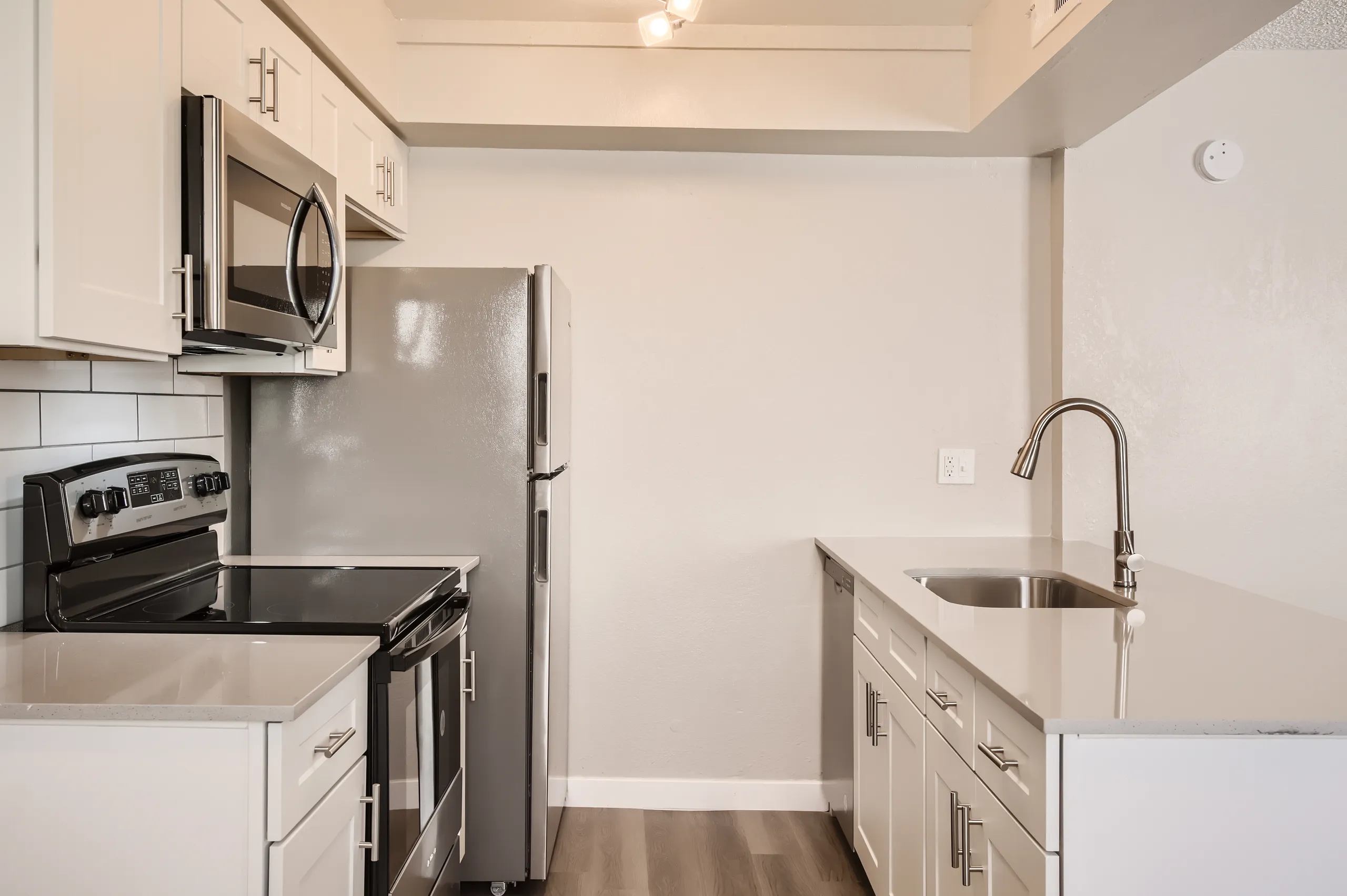 Kitchen with white cabinetry, stainless appliances, and quartz counters