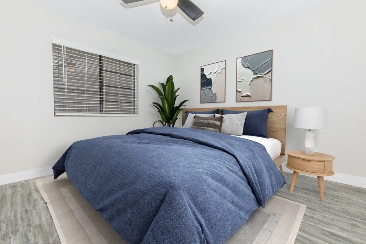 Primary bedroom, wood-style plank flooring, wood headboard, blue bedding, pendant lighting