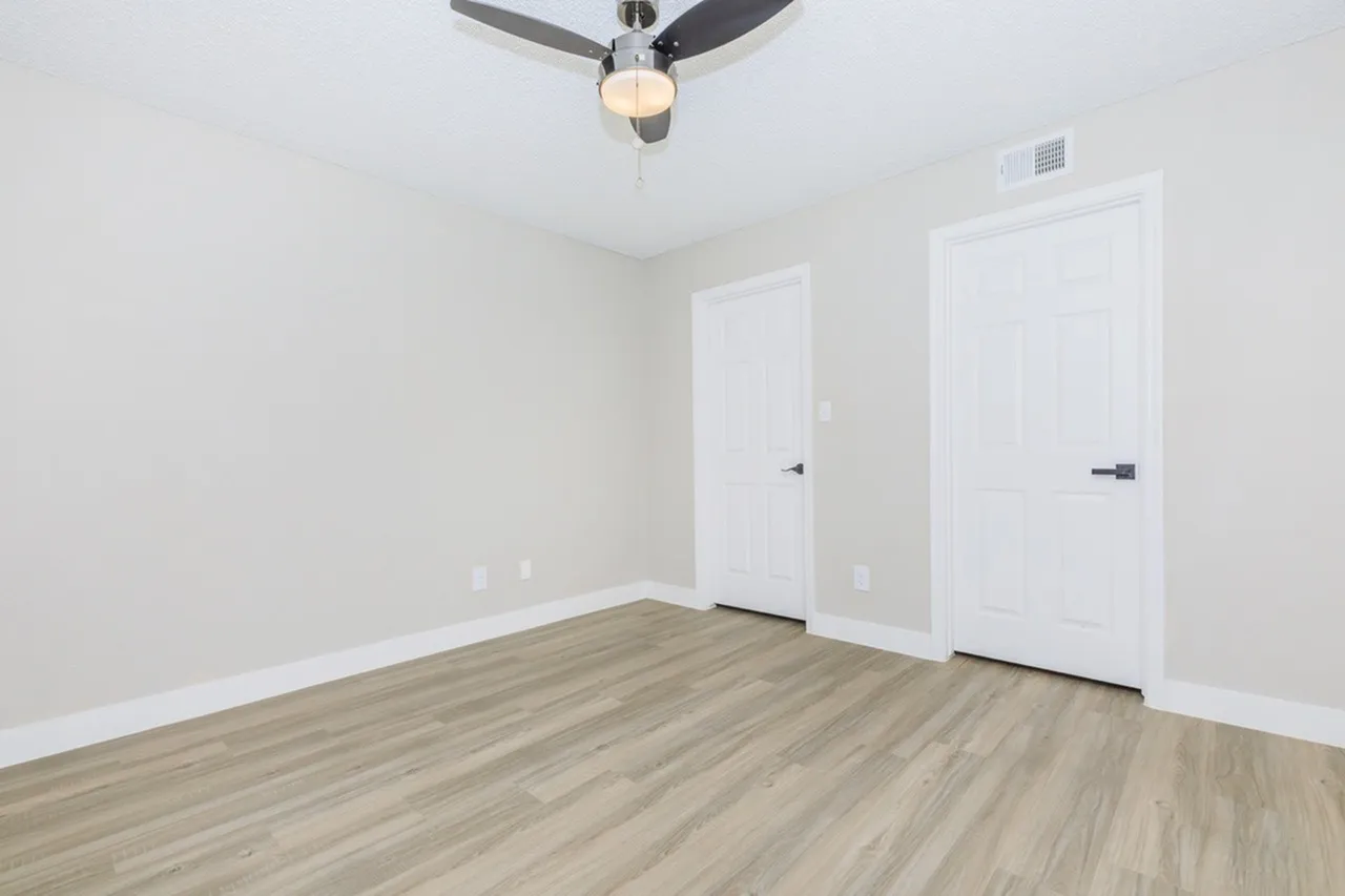 Primary bedroom, wood-style plank flooring, ceiling fan, white panel doors