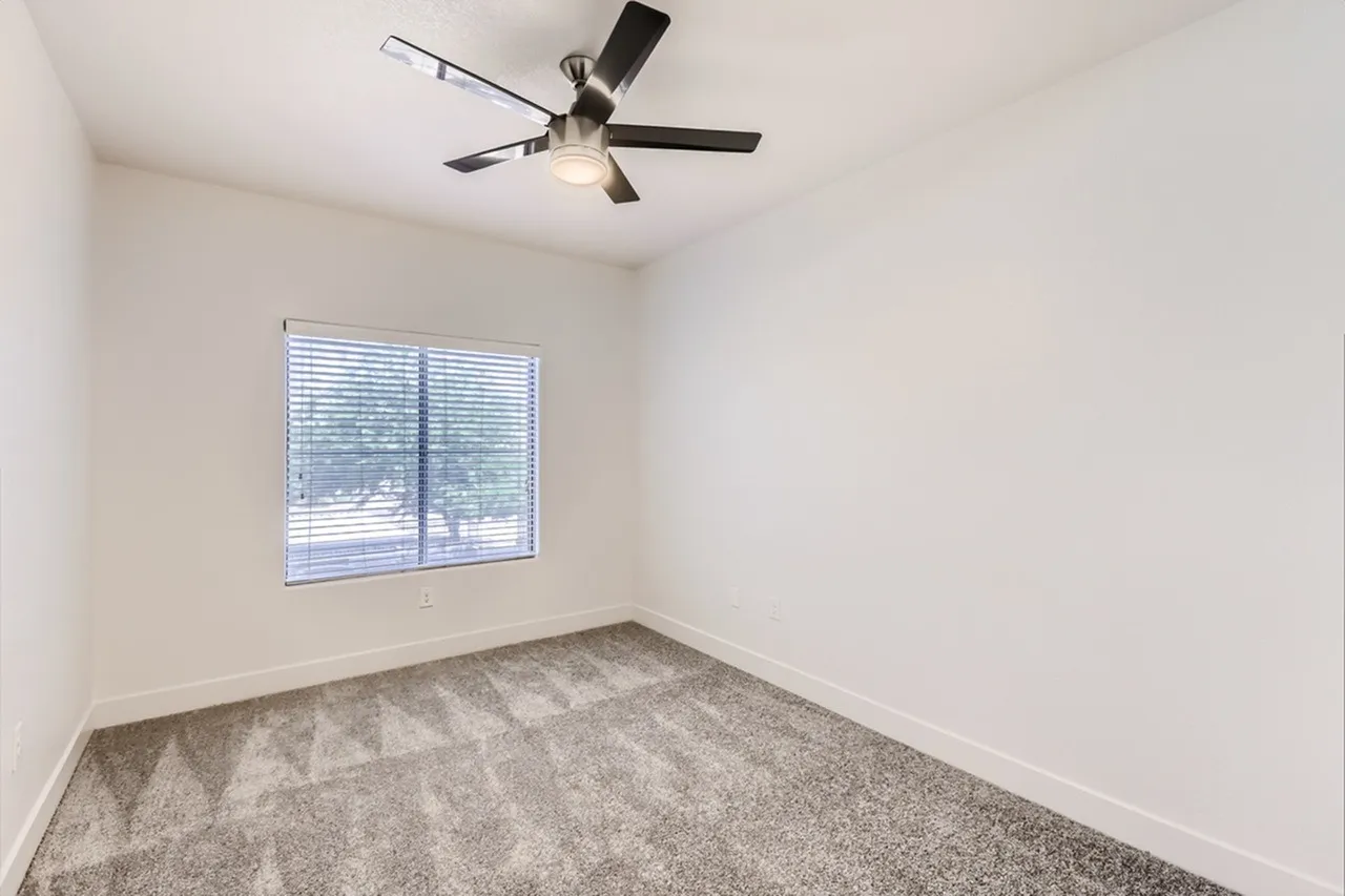 Bedroom, gray carpet flooring, ceiling fan with light, window with blinds