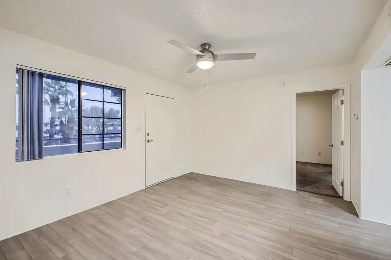 Living room, wood-style plank flooring, ceiling fan, entry door, large window