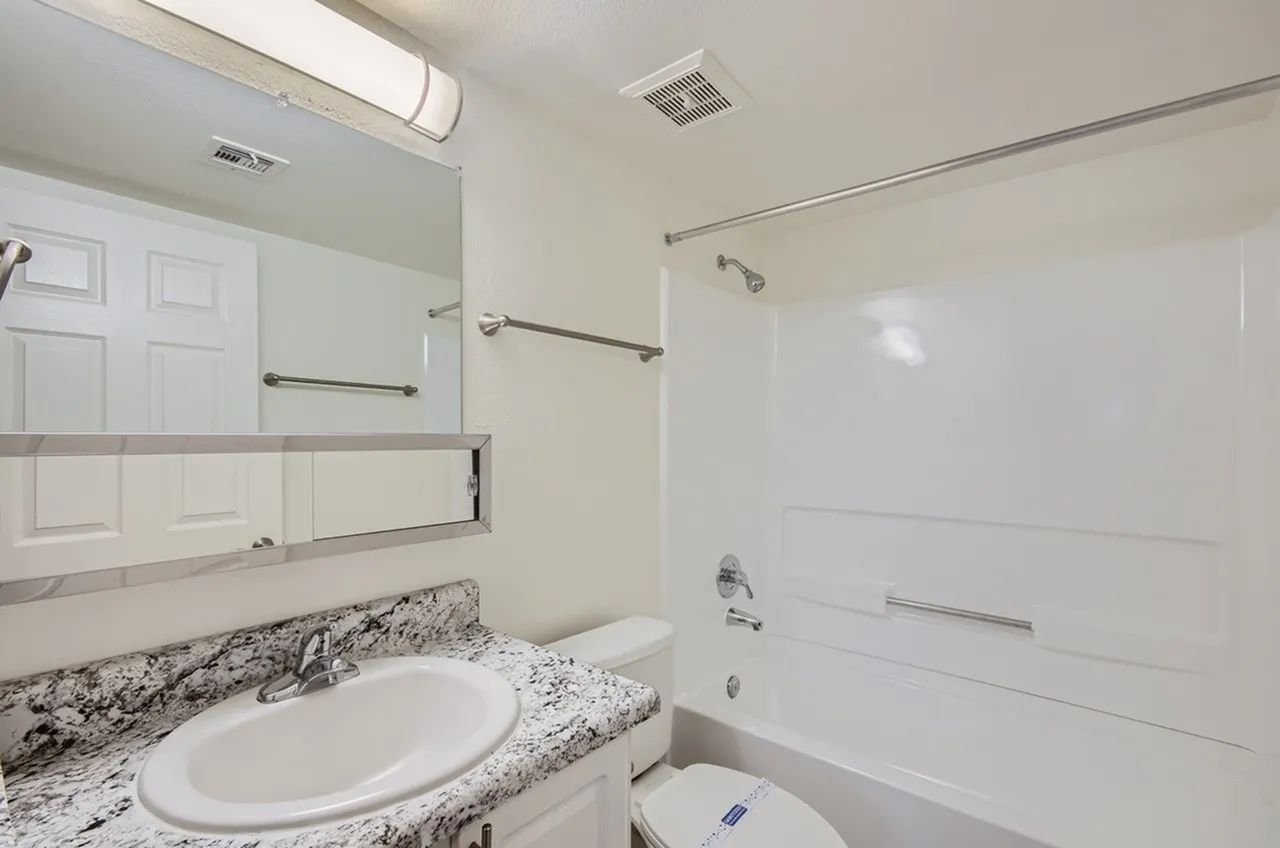 Bathroom, granite countertop, round white sink, framed mirror, white shower enclosure