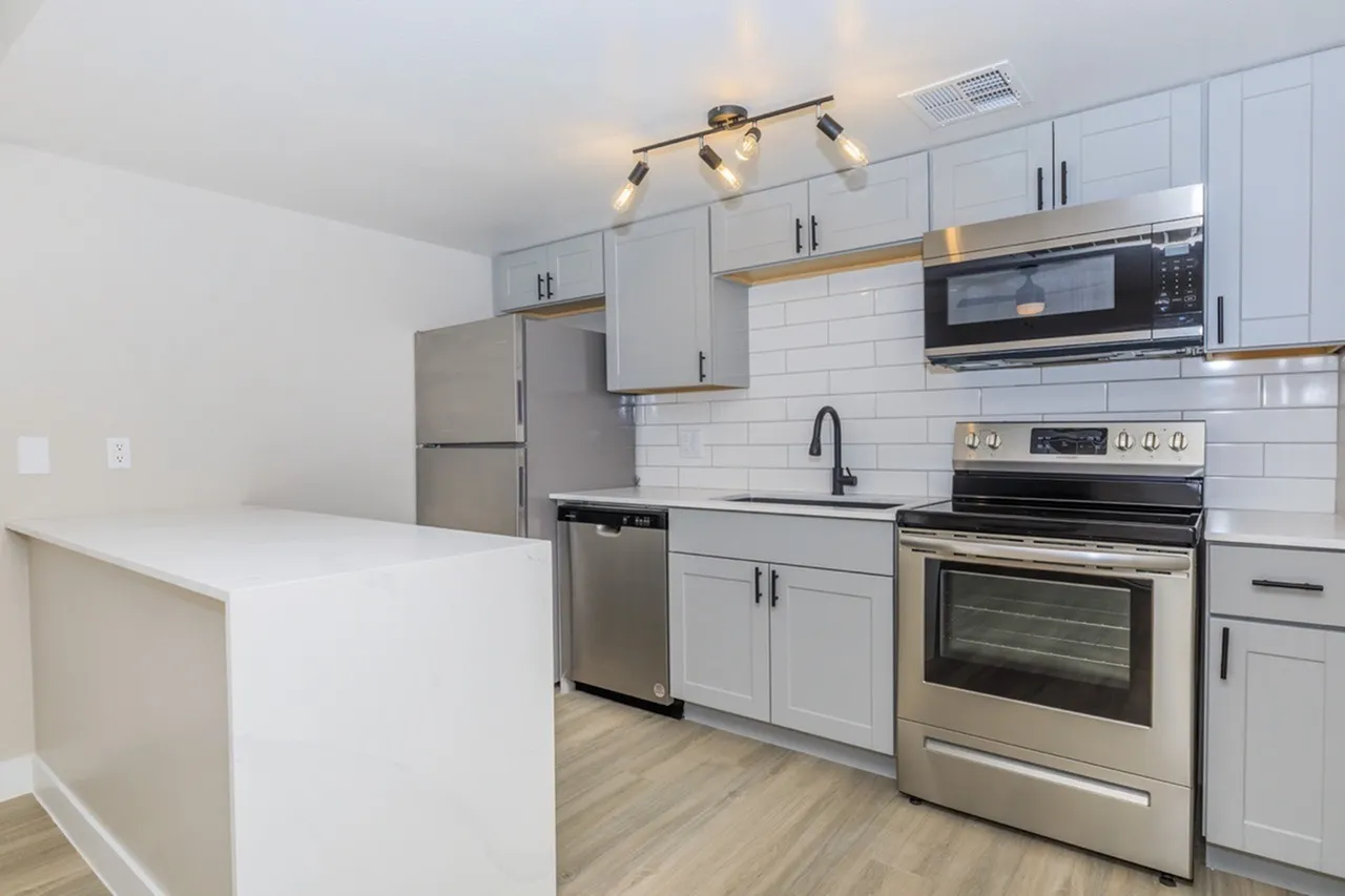 Kitchen, white shaker cabinetry, quartz countertop island, stainless appliances, white subway tile backsplash, wood-style plank flooring