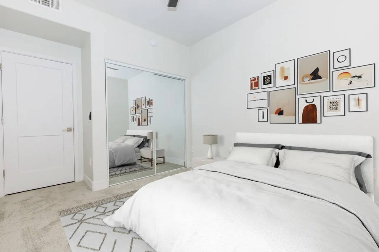 Primary bedroom, wood-style plank flooring, white bedding, wall gallery art, ensuite bathroom