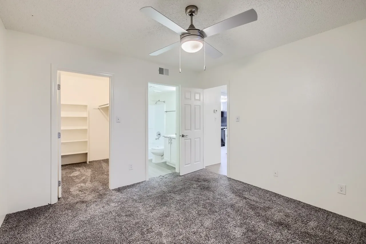 Primary bedroom, carpet flooring, ceiling fan with light, walk-in closet, ensuite bathroom