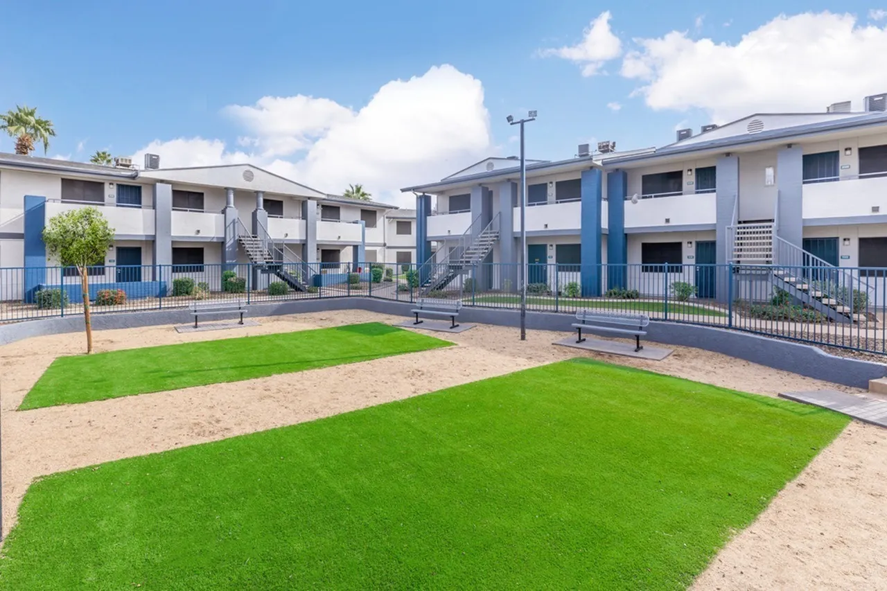 Courtyard with green lawn, sandy area, benches, apartment buildings, blue accents, Phoenix